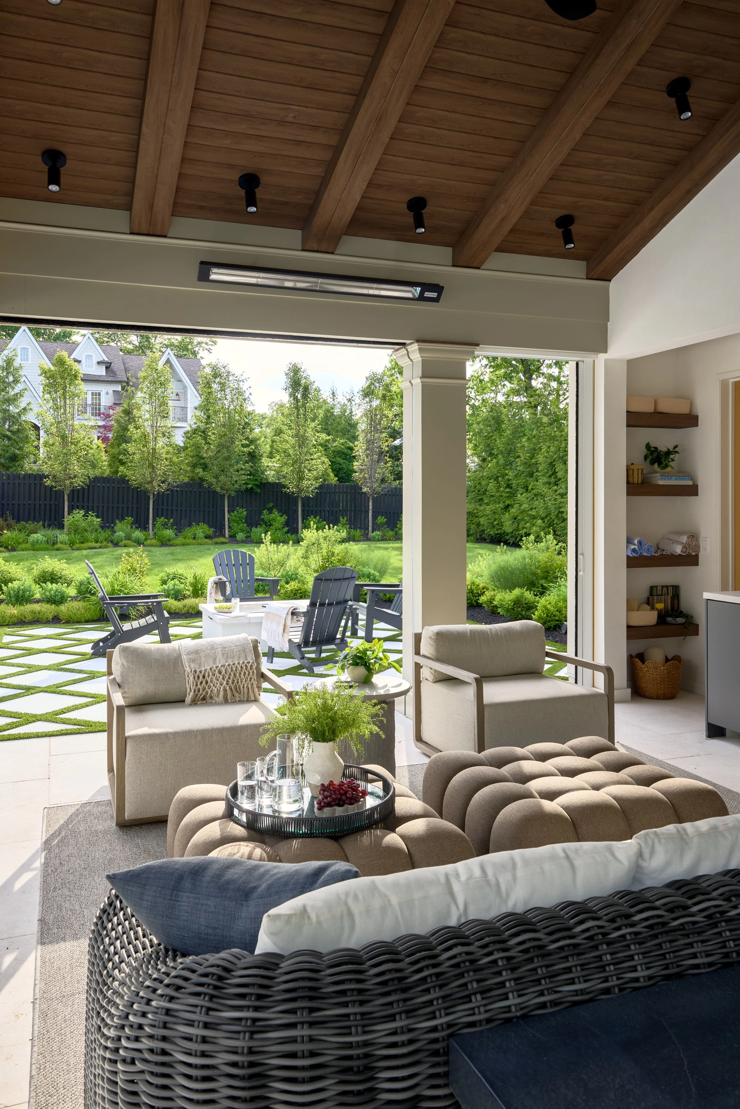 Covered pool pavilion with exposed wood beams, integrated heaters, recessed lighting and open views of a landscaped backyard.jpg