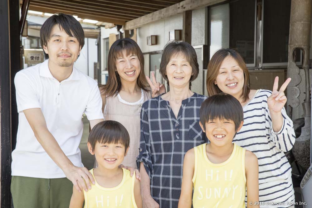 オーナーの今村マスエさん(後列右から2人目)のご家族と入口の前で撮影