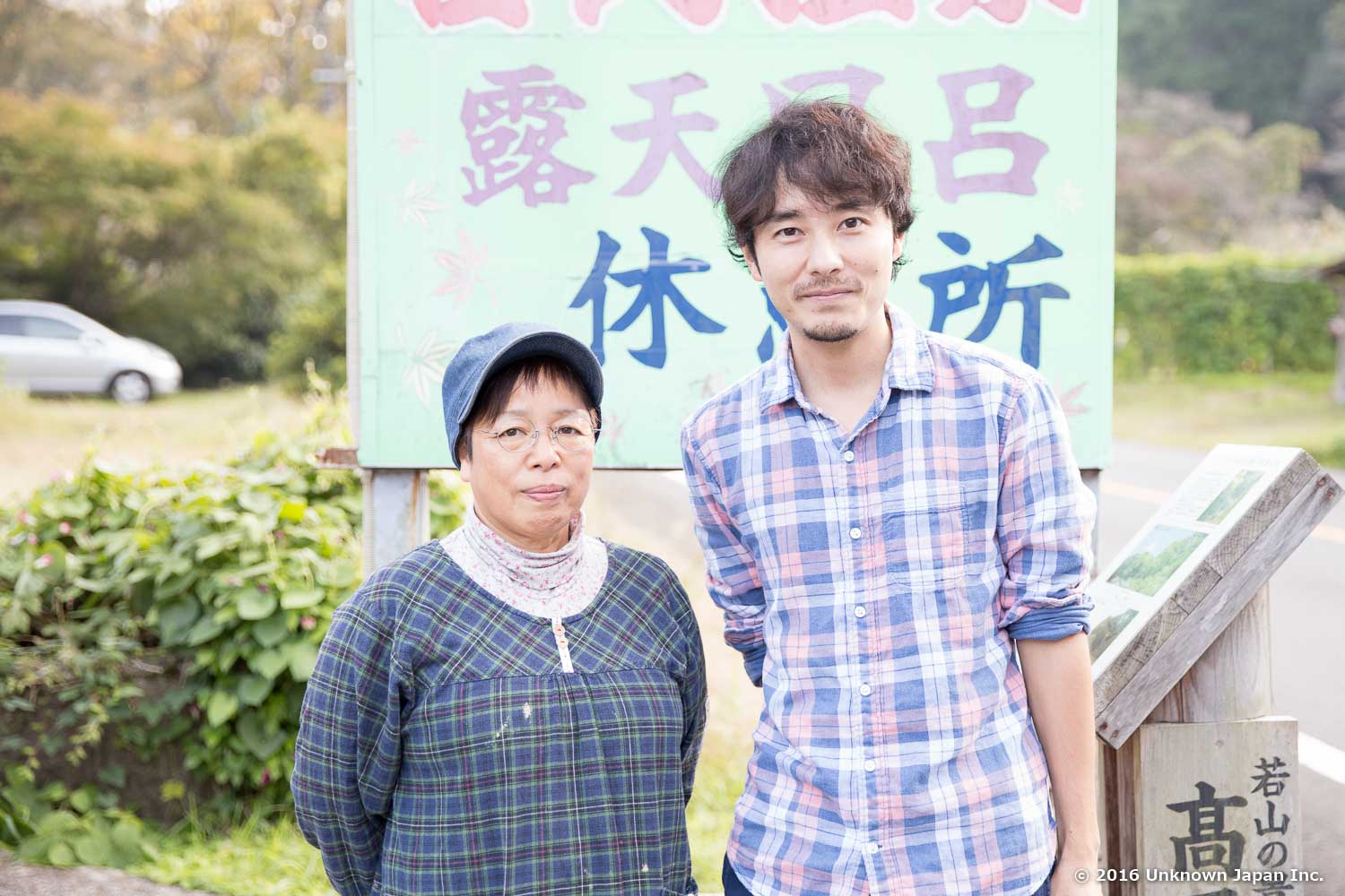オーナーの松葉千恵子さんと看板の前で撮影