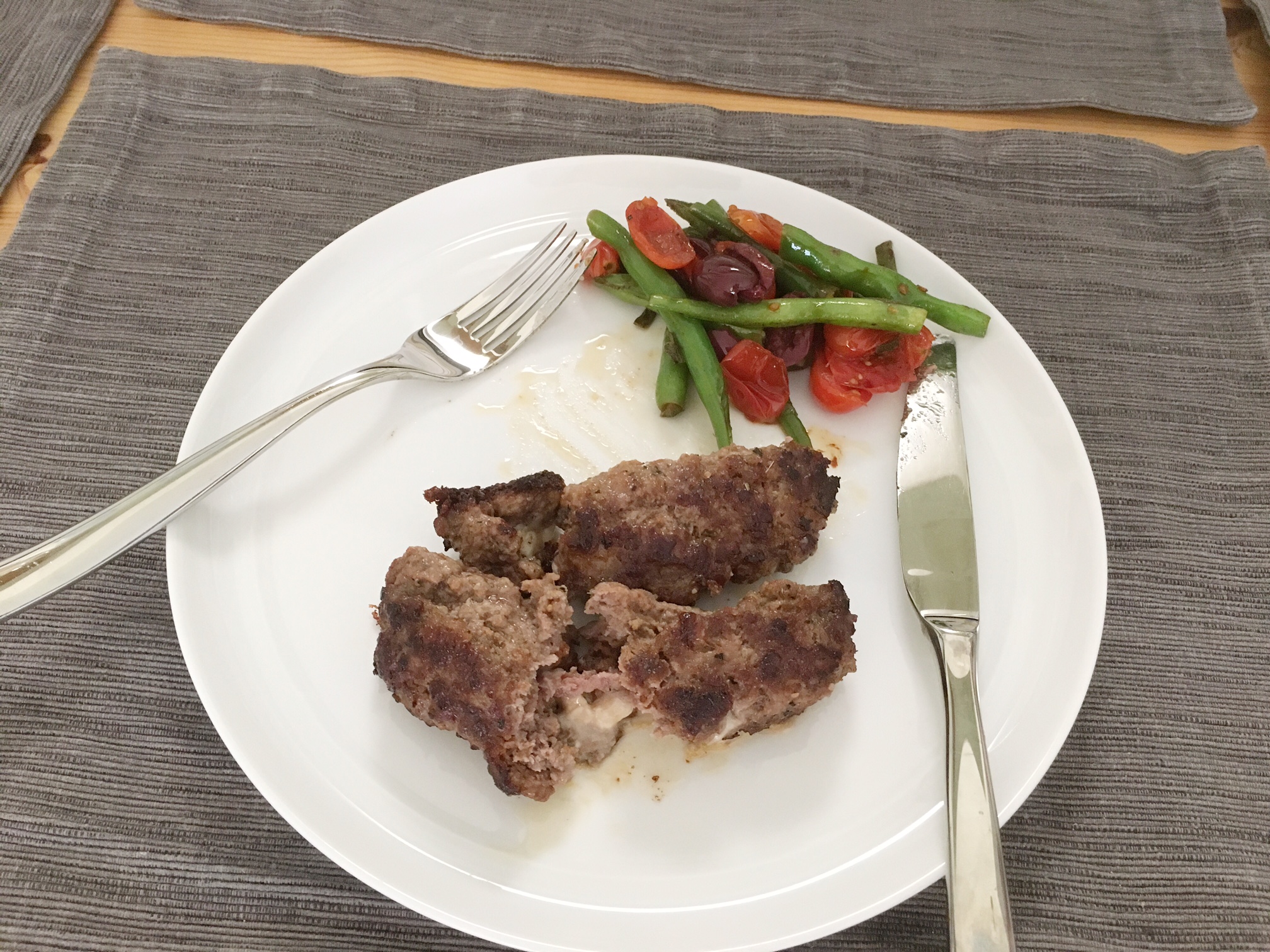 Feta-stuffed beeftekia with green bean, tomato, and Kalamata olive salad.
