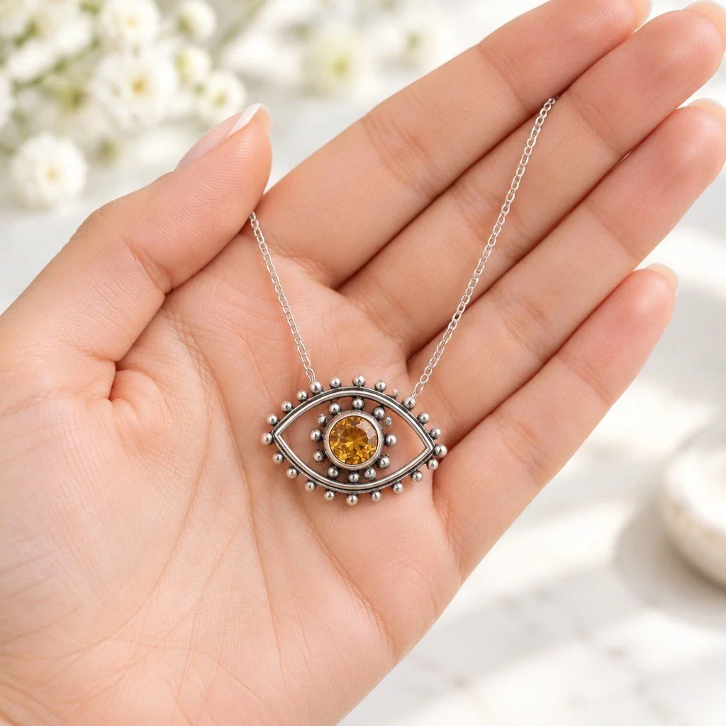 Sterling silver citrine Evil Eye necklace resting in a hand, showing its size and detailed silver beadwork.