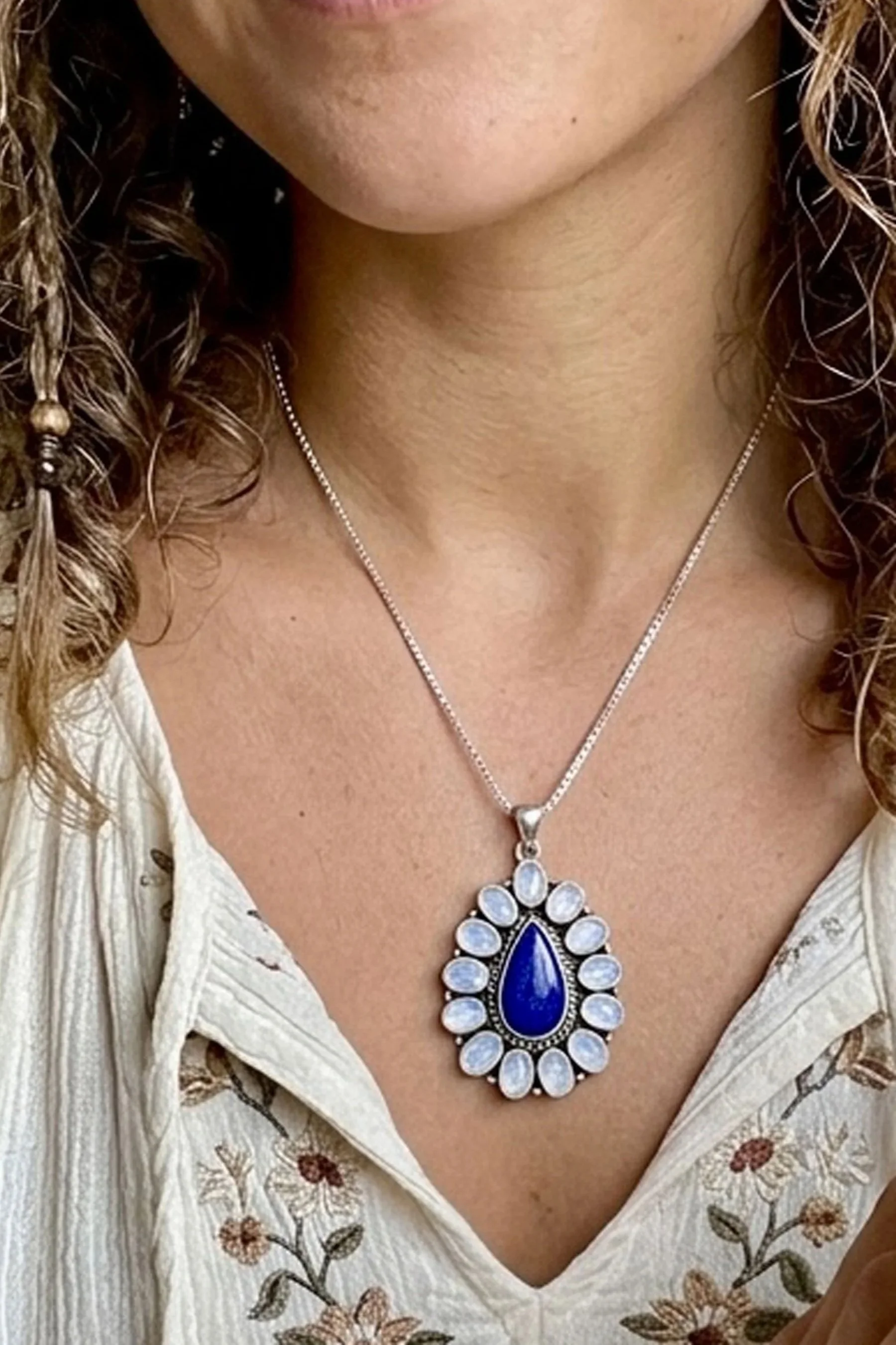 Woman wearing a handcrafted sterling silver Lapis Lazuli and Rainbow Moonstone pendant necklace featuring deep blue and iridescent natural gemstones.