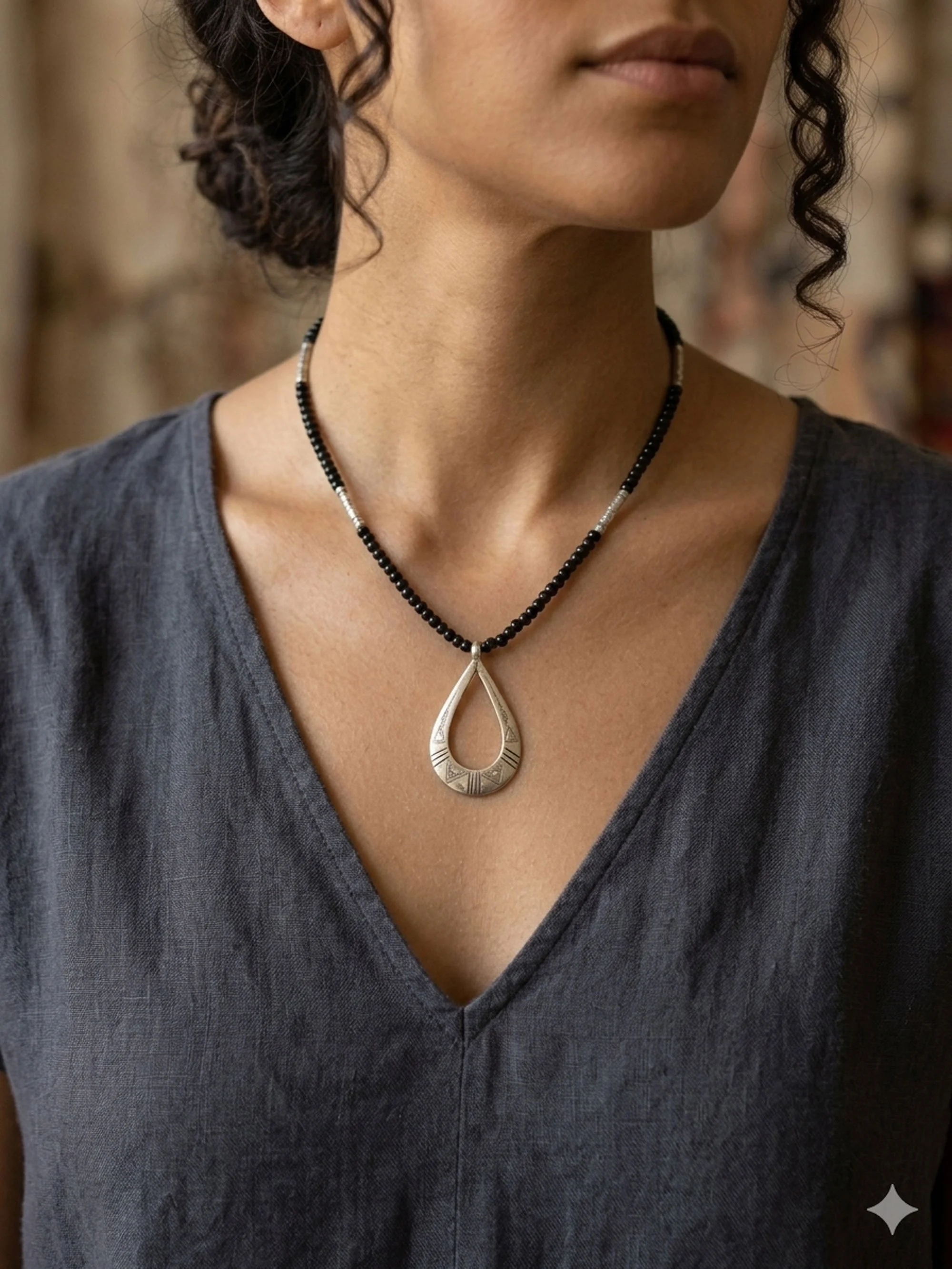 Woman wearing handcrafted sterling silver teardrop pendant necklace with black beaded chain and minimalist boho styling.
