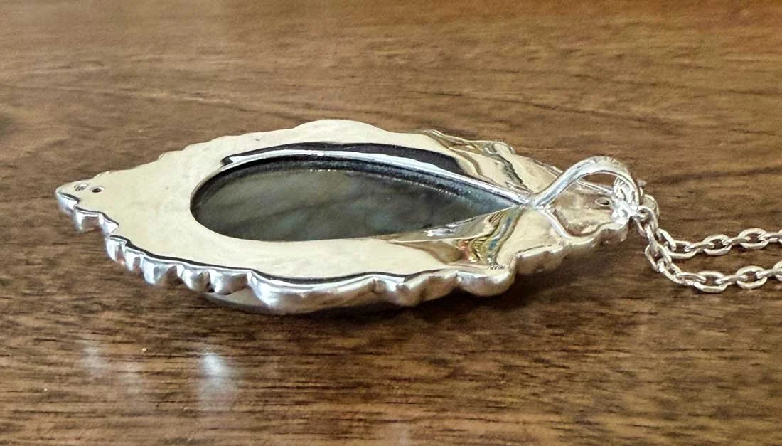 Sterling silver pendant featuring a teardrop-shaped labradorite gemstone with iridescent blue and green flashes, handmade by artisans in Bali.
