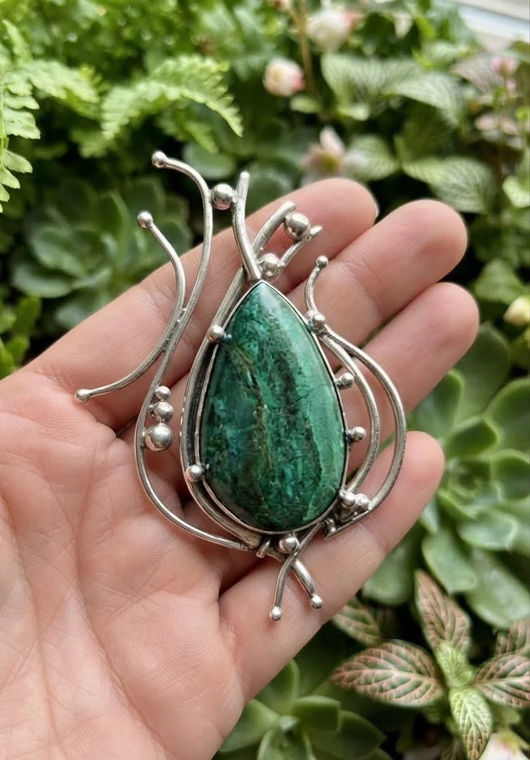 Natural green chrysocolla gemstone pendant in sterling silver shown in hand for size and scale