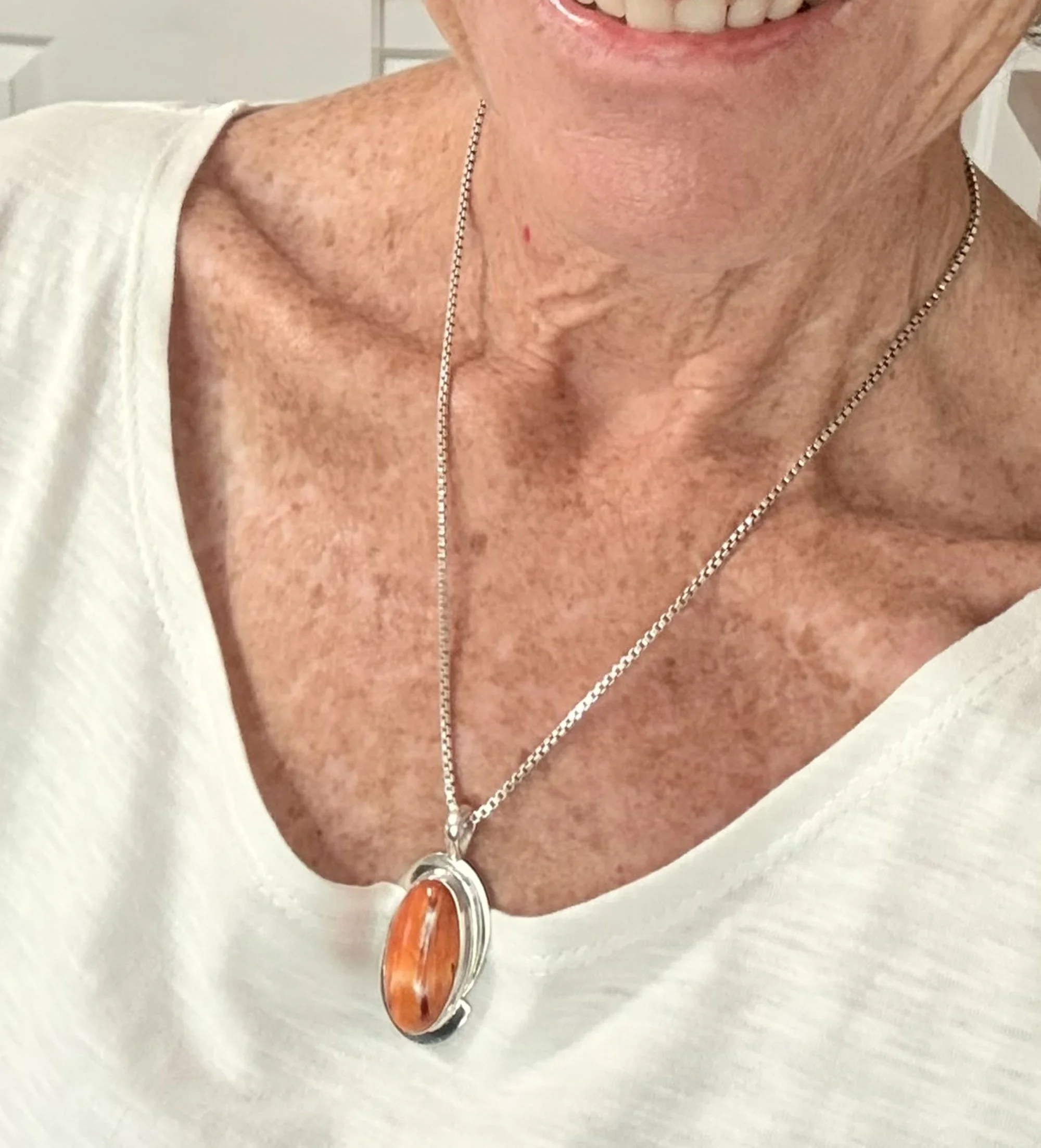 Woman wearing a genuine orange Spiny Oyster Shell pendant in sterling silver.