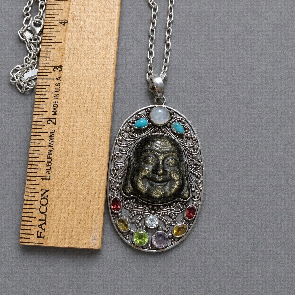 Carved obsidian Buddha pendant beside a ruler showing its approximate size