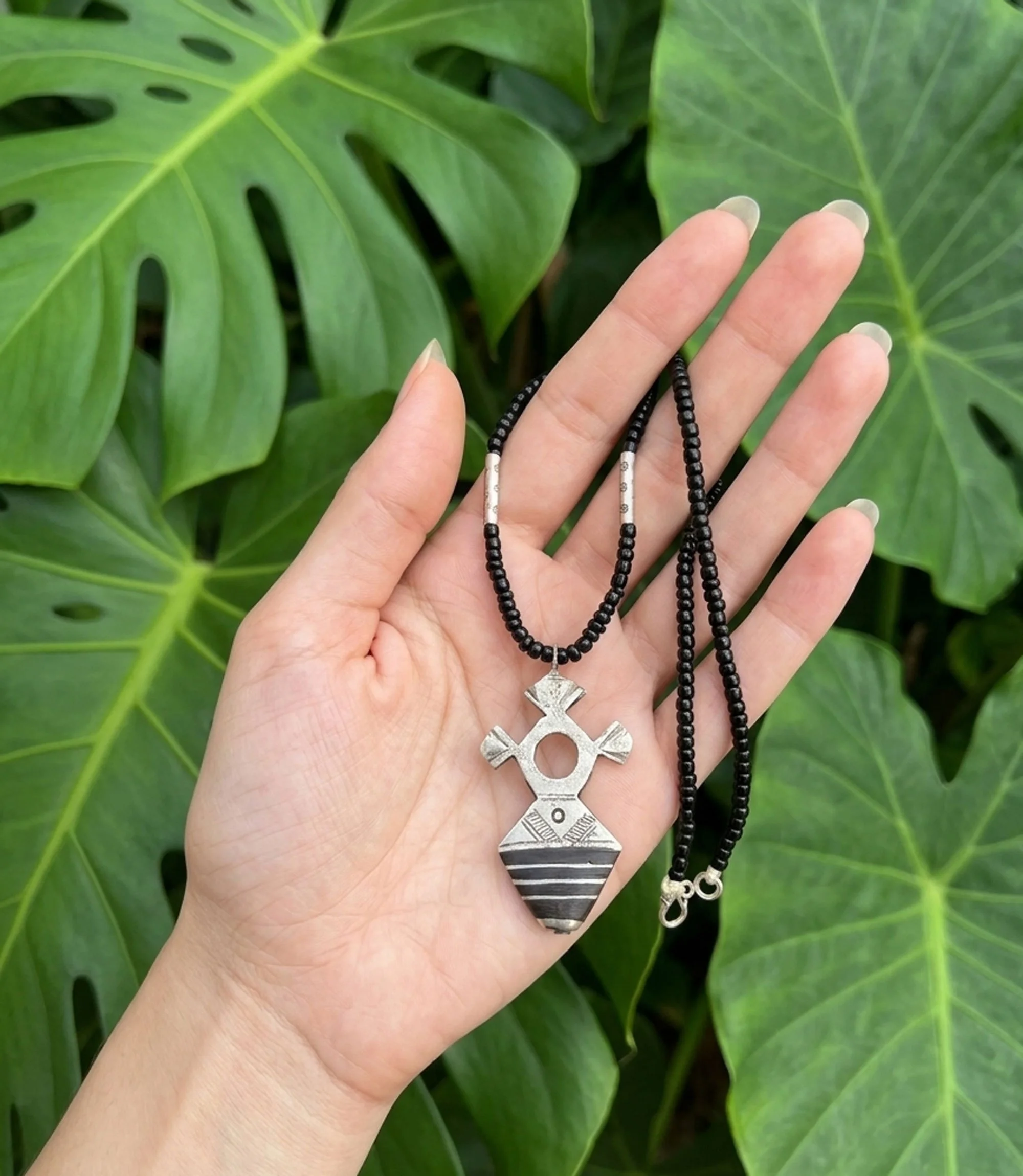 Handcrafted Moroccan Tuareg Cross necklace held in hand.