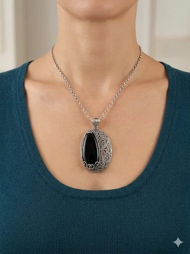 Handcrafted sterling silver pendant featuring a polished black onyx stone with ornate filigree metalwork,