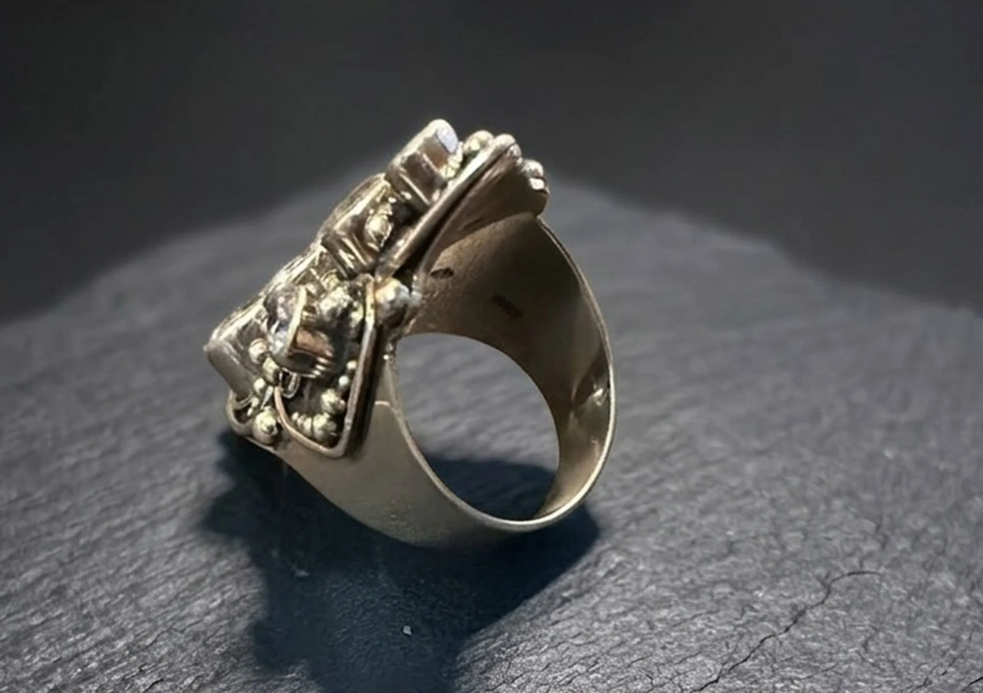 Side view of ornate sterling silver statement ring showing raised multi-stone setting and detailed granulated accents