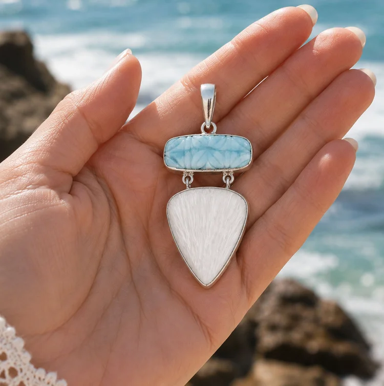Larimar and white scolecite sterling silver pendant held in a hand by the sea