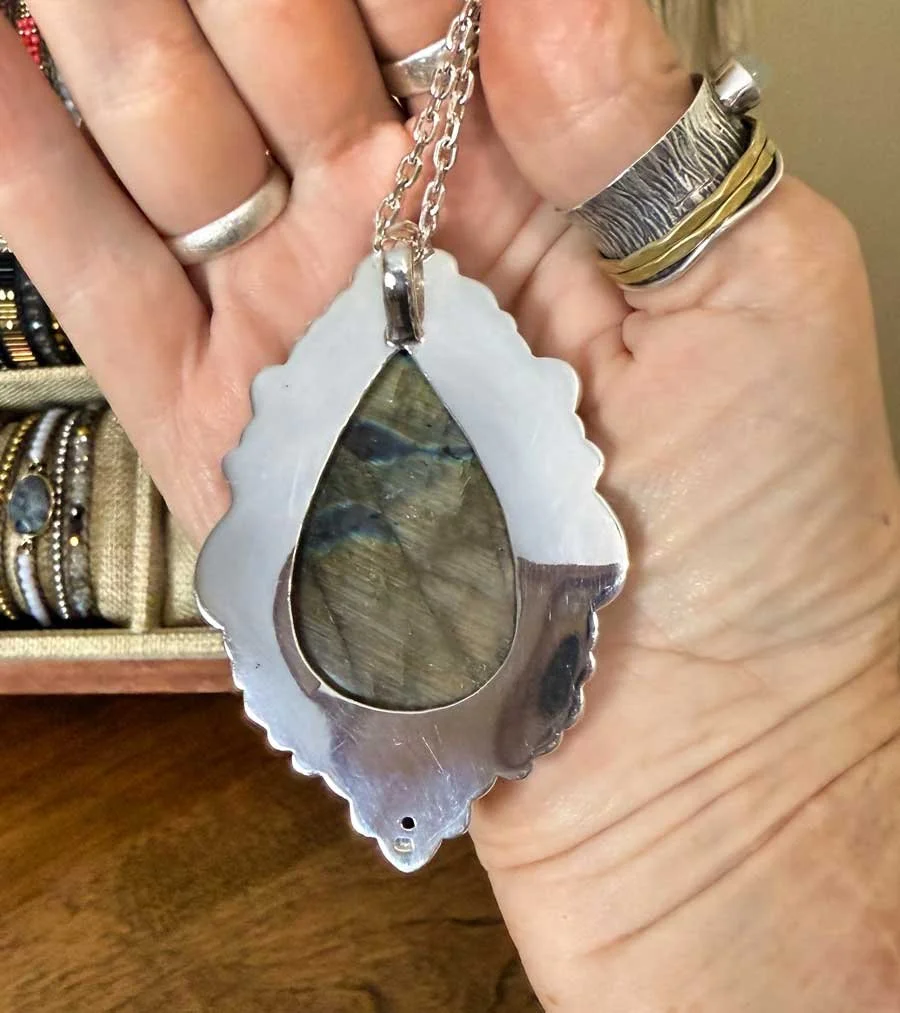 Sterling silver pendant featuring a teardrop-shaped labradorite gemstone with iridescent blue and green flashes, handmade by artisans in Bali.