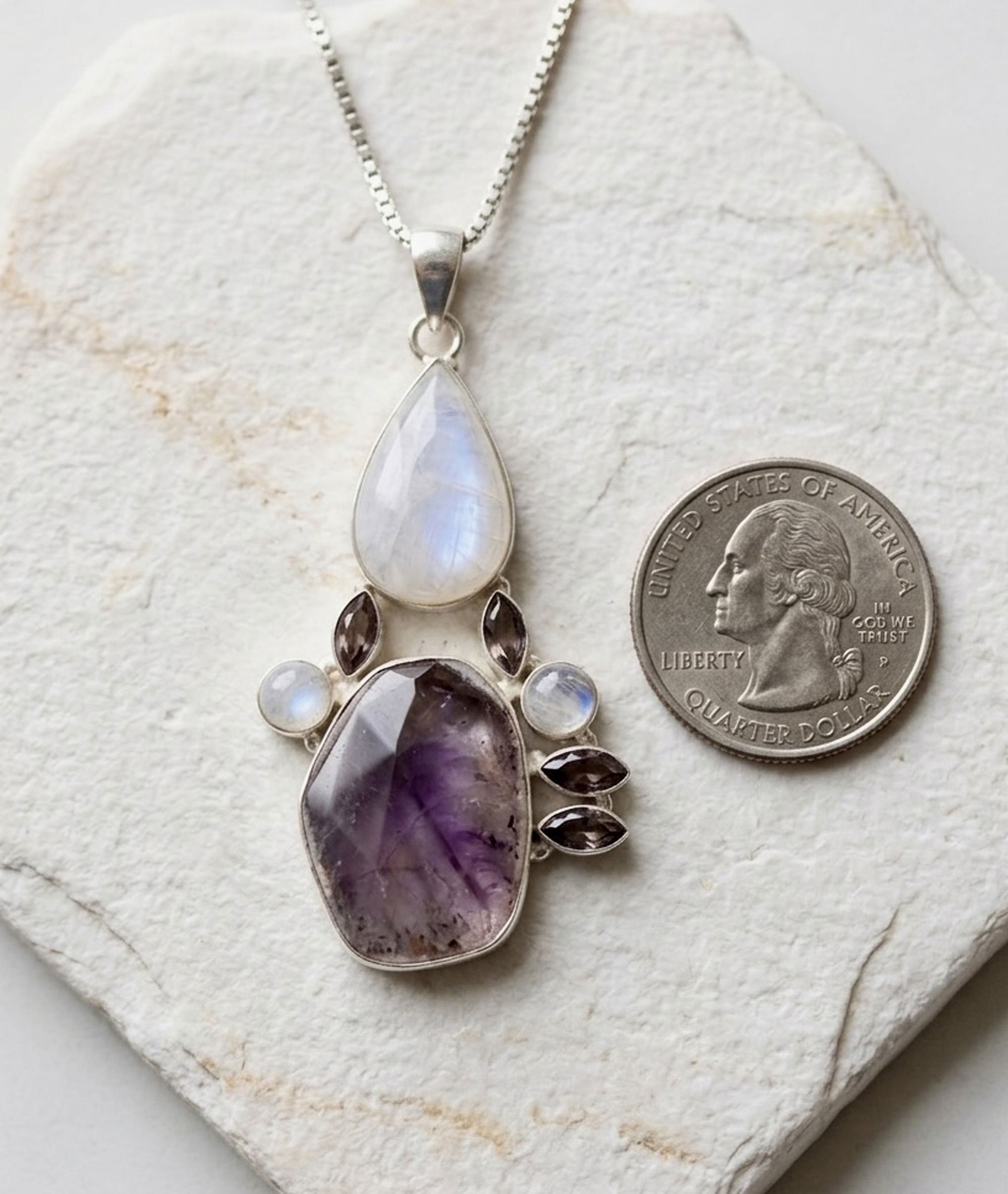 Auralite 23, moonstone, and amethyst sterling silver pendant shown beside a U.S. quarter for size comparison.