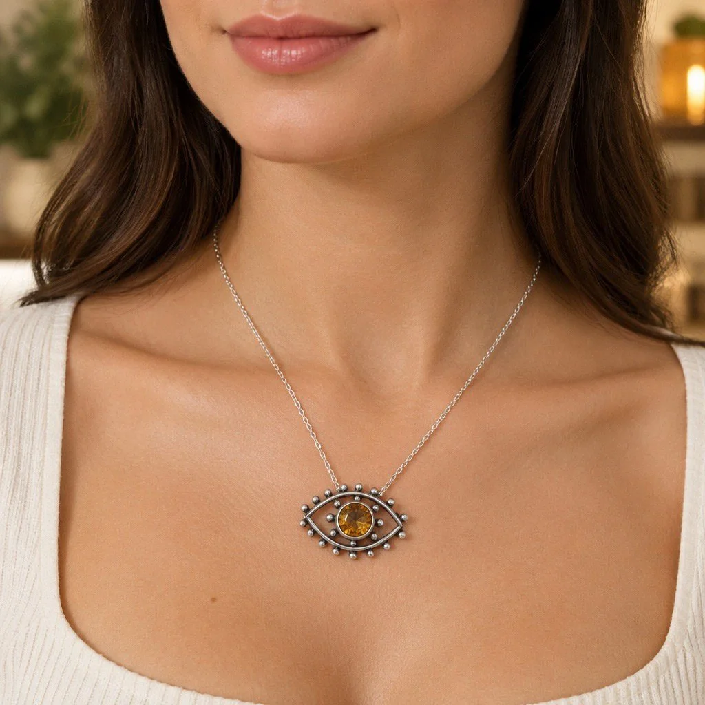 Woman wearing a sterling silver Evil Eye necklace featuring a golden citrine gemstone.