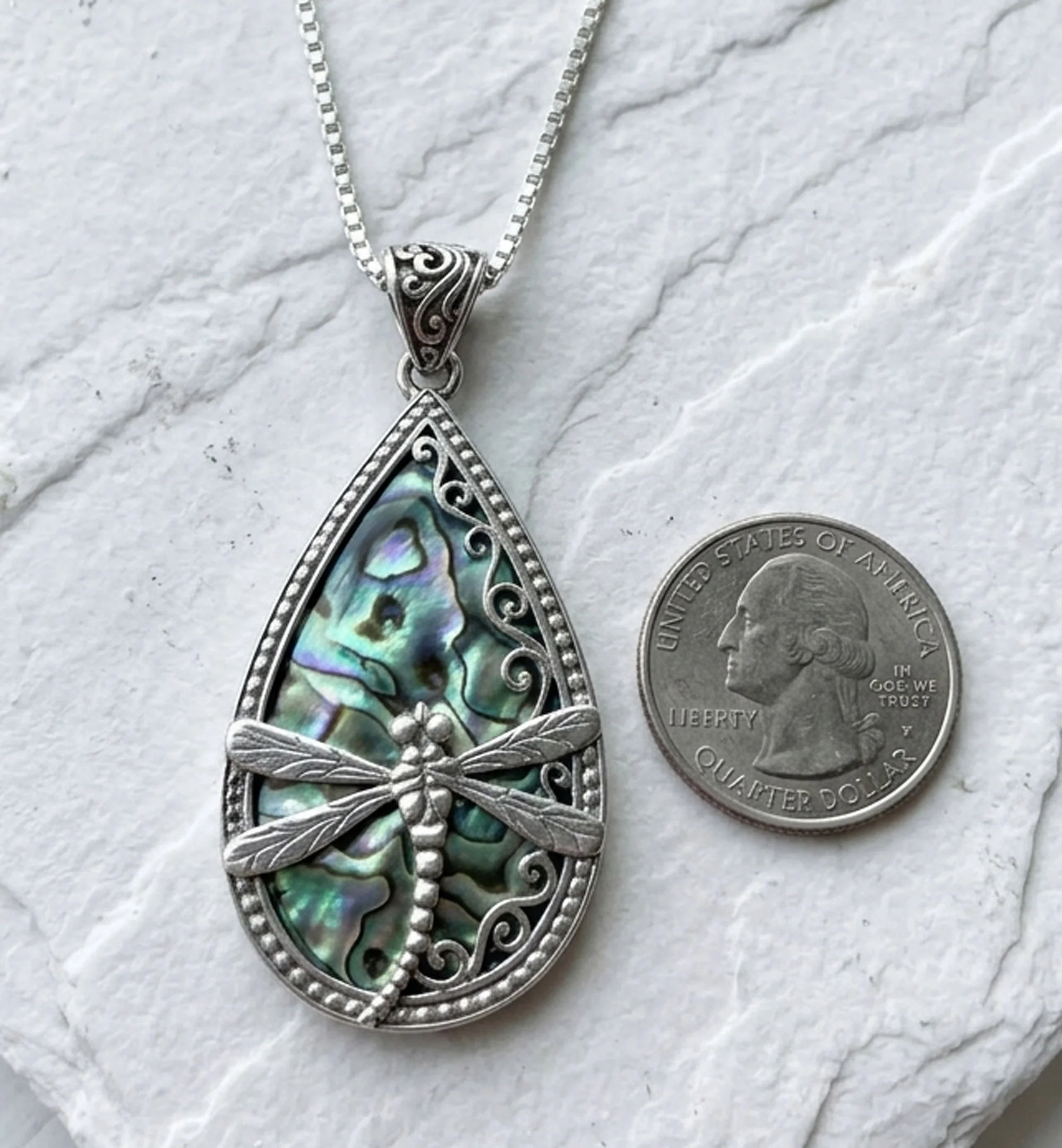 Dragonfly sterling silver pendant featuring natural abalone shell displayed beside a quarter for size comparison.