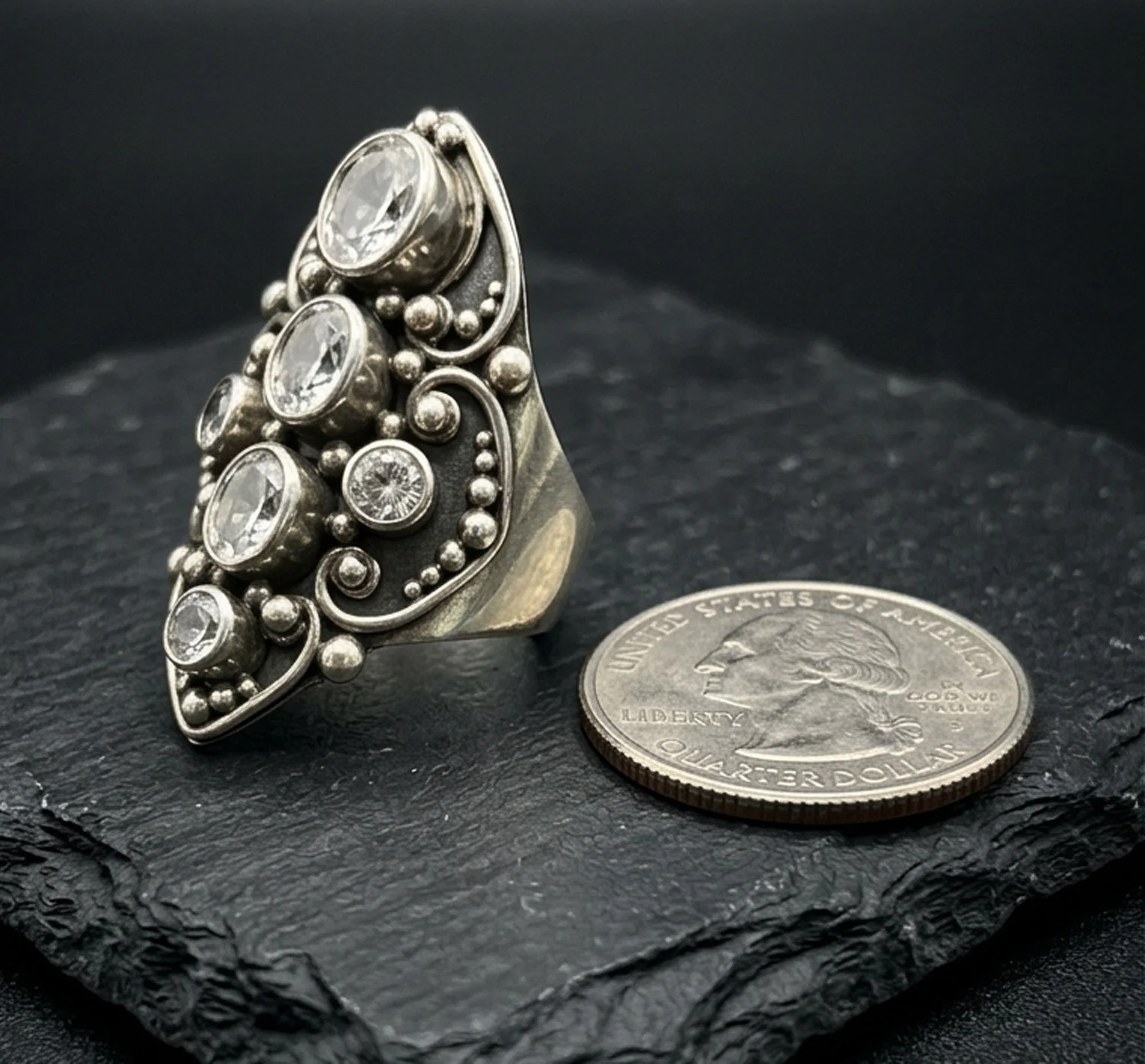 Vintage sterling silver statement ring with multiple Zircon gemstones and ornate granulation design, shown next to a U.S. quarter for scale