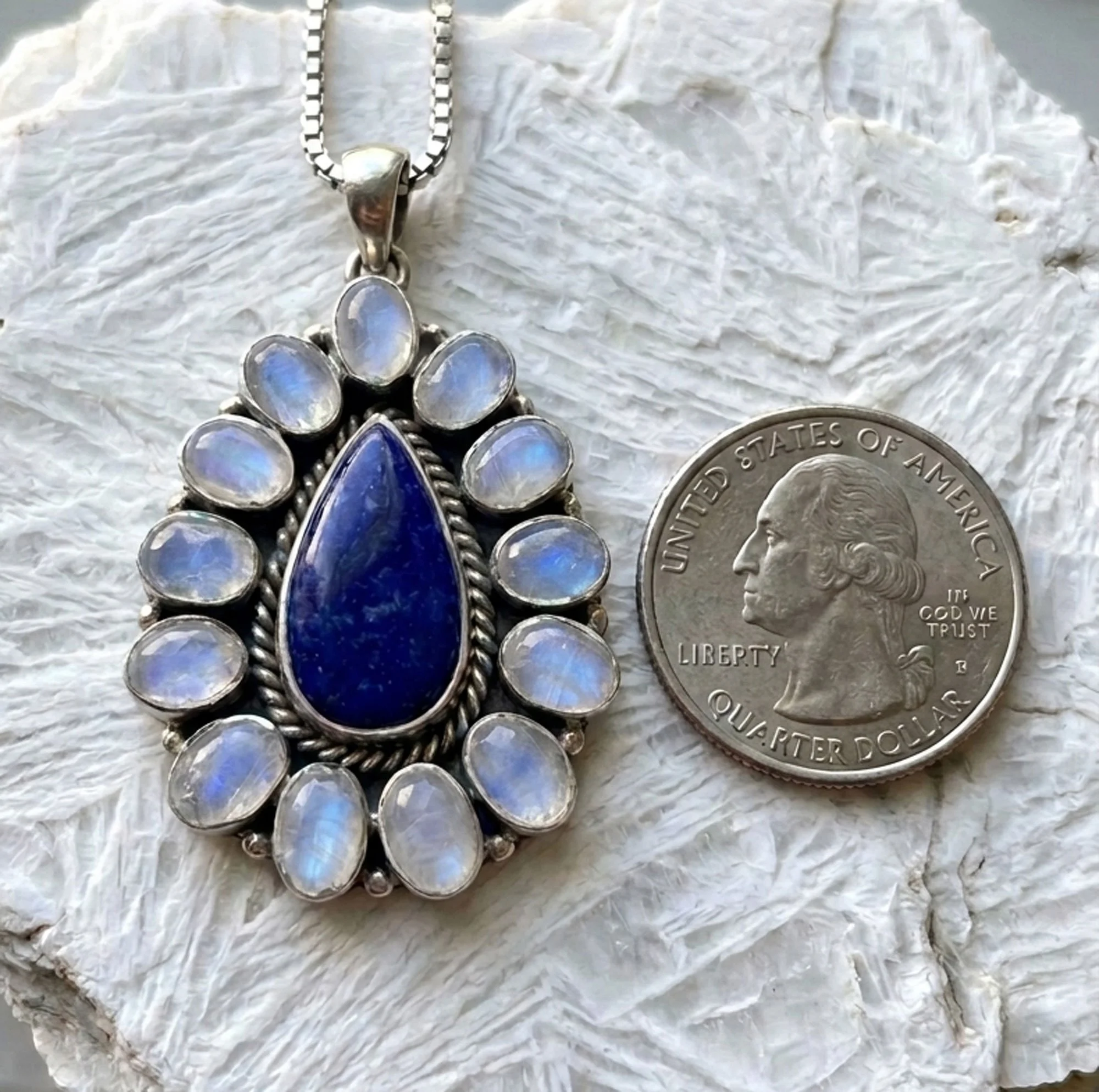 Sterling silver Lapis Lazuli and Rainbow Moonstone pendant displayed beside a U.S. quarter for size reference, showcasing natural blue gemstones and handcrafted Balinese silverwork.