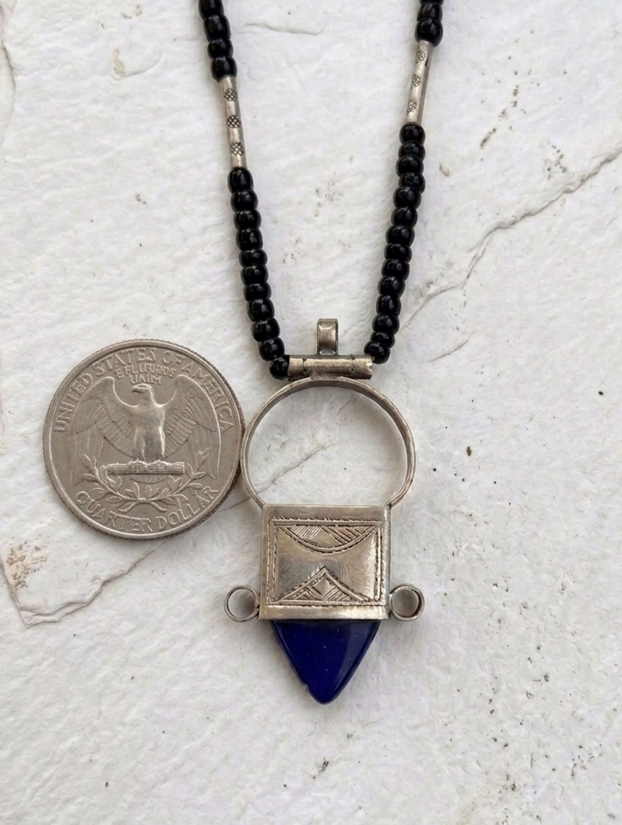 Blue stone Moroccan artisan necklace shown beside a quarter for size comparison.