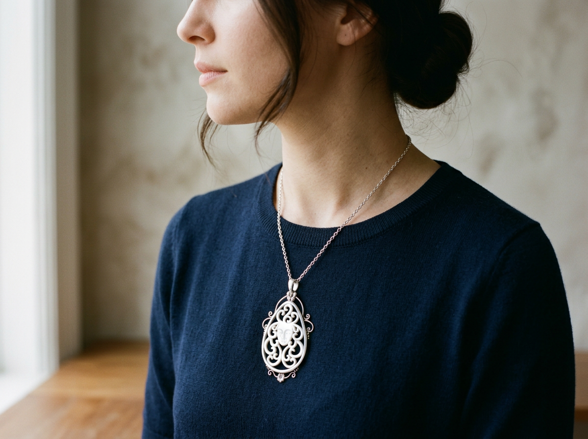 Hand-carved mother of pearl face pendant with swirling openwork in an ornate silver setting