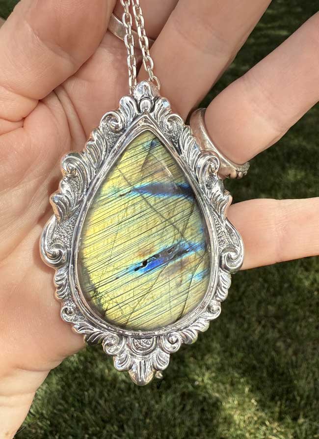 Sterling silver pendant featuring a teardrop-shaped labradorite gemstone with iridescent blue and green flashes, handmade by artisans in Bali.