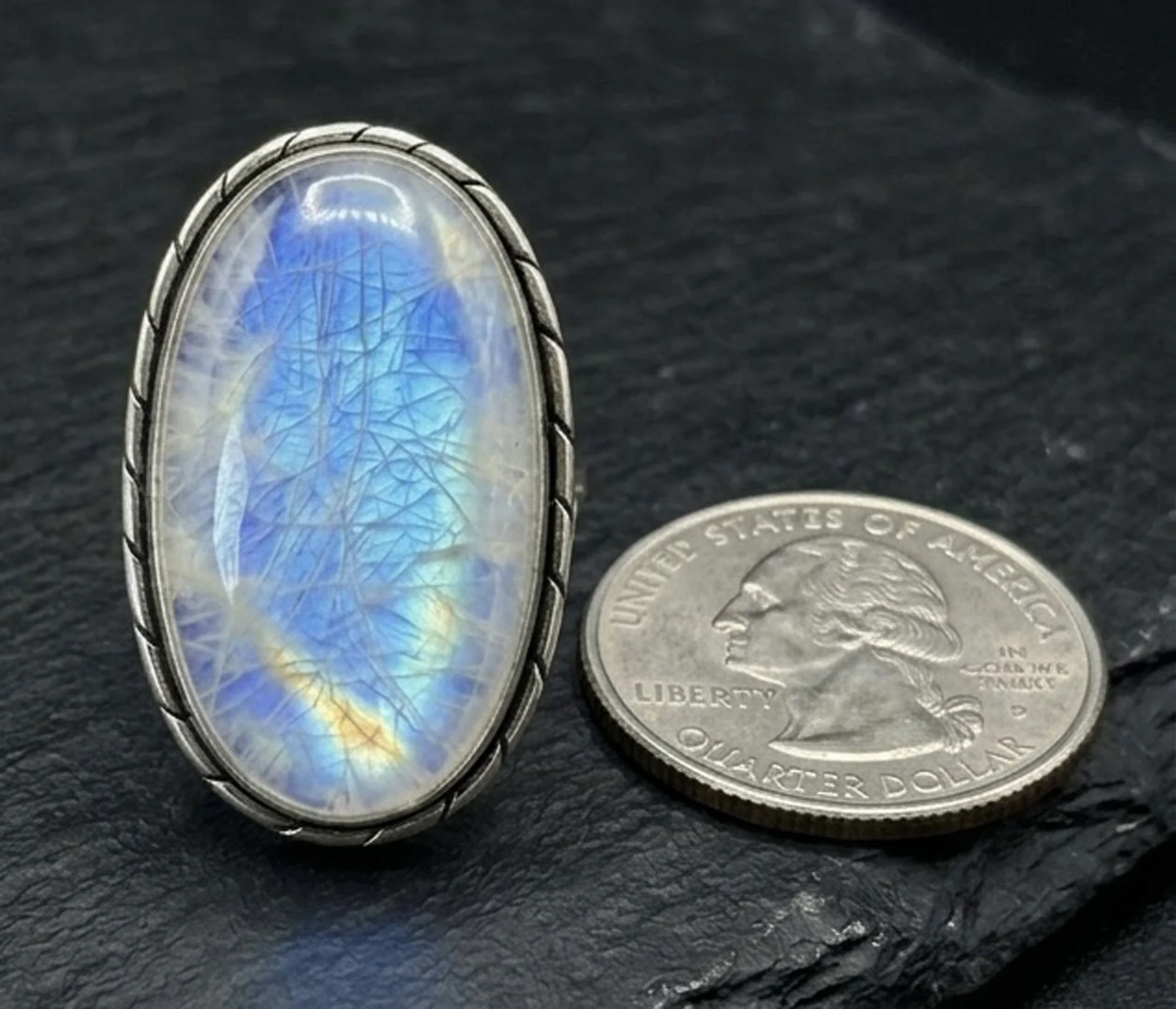 Blue flash rainbow moonstone oval ring sterling silver boho artisan jewelry shown next to a quarter for size