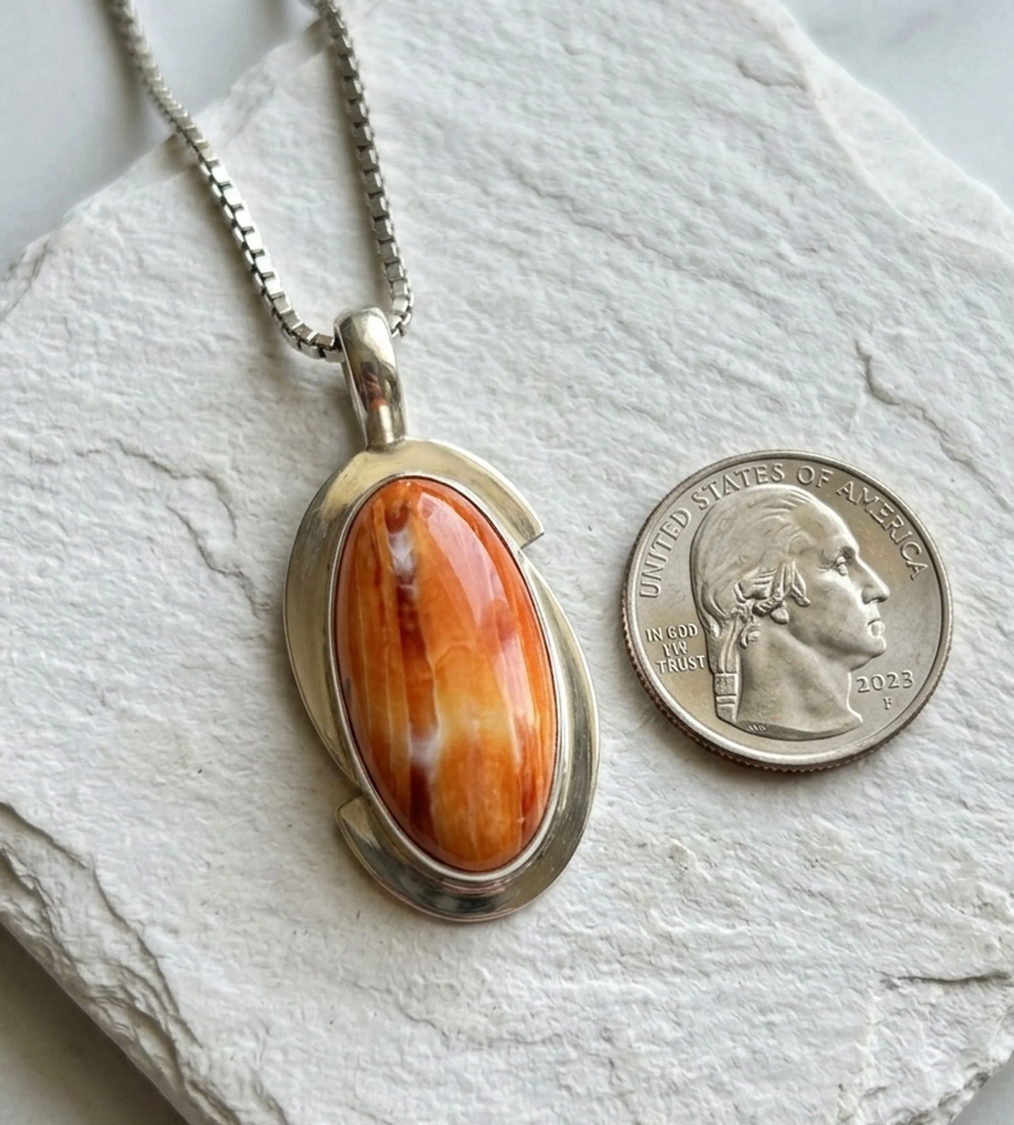 One-of-a-kind sterling silver Spiny Oyster Shell pendant shown beside a quarter for size comparison.