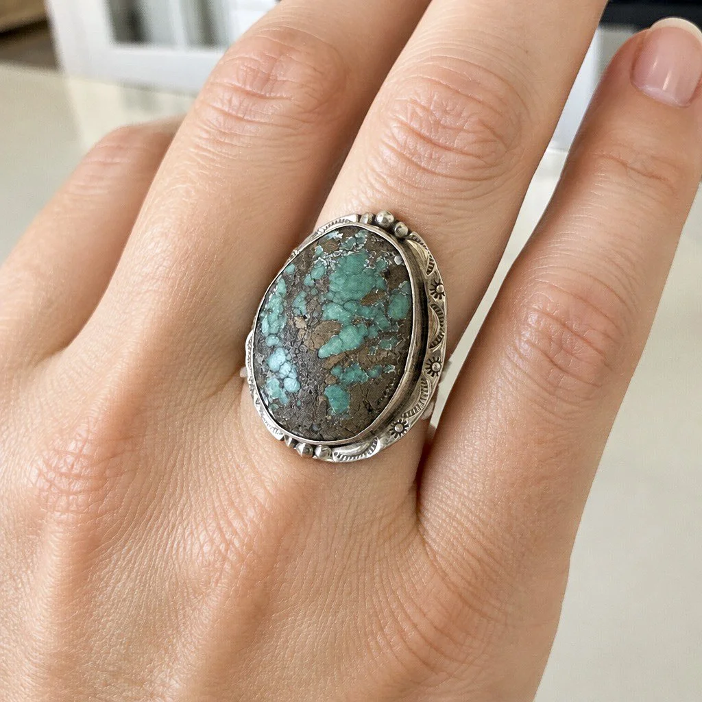 Natural turquoise sterling silver statement ring with detailed Southwestern silverwork shown on hand