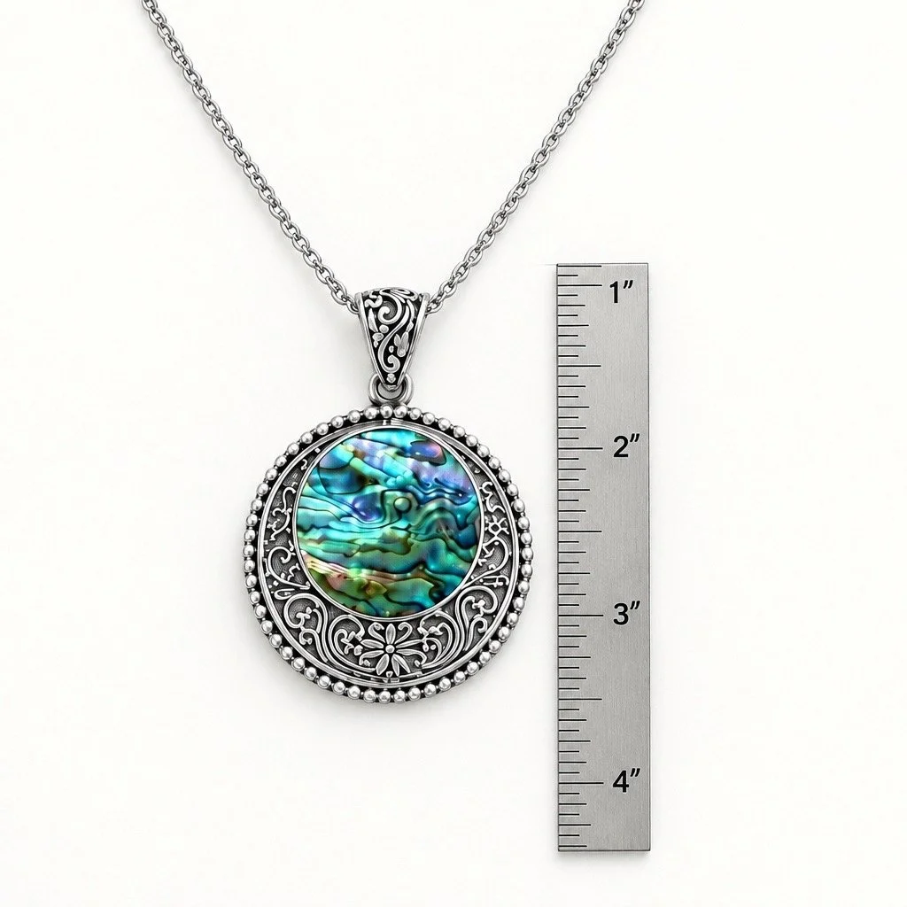 Natural abalone shell sterling silver pendant with intricate Bali silver scrollwork and detailed bail next to ruler for scale