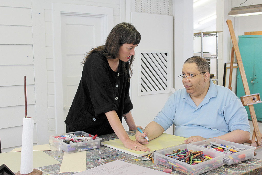 Longtime Studio By the Tracks student, Melvin, recieves help from a teacher as he begins working on a new piece for the Art From the Heart fundraiser on June 12. Journal photo by Emily Williams.
