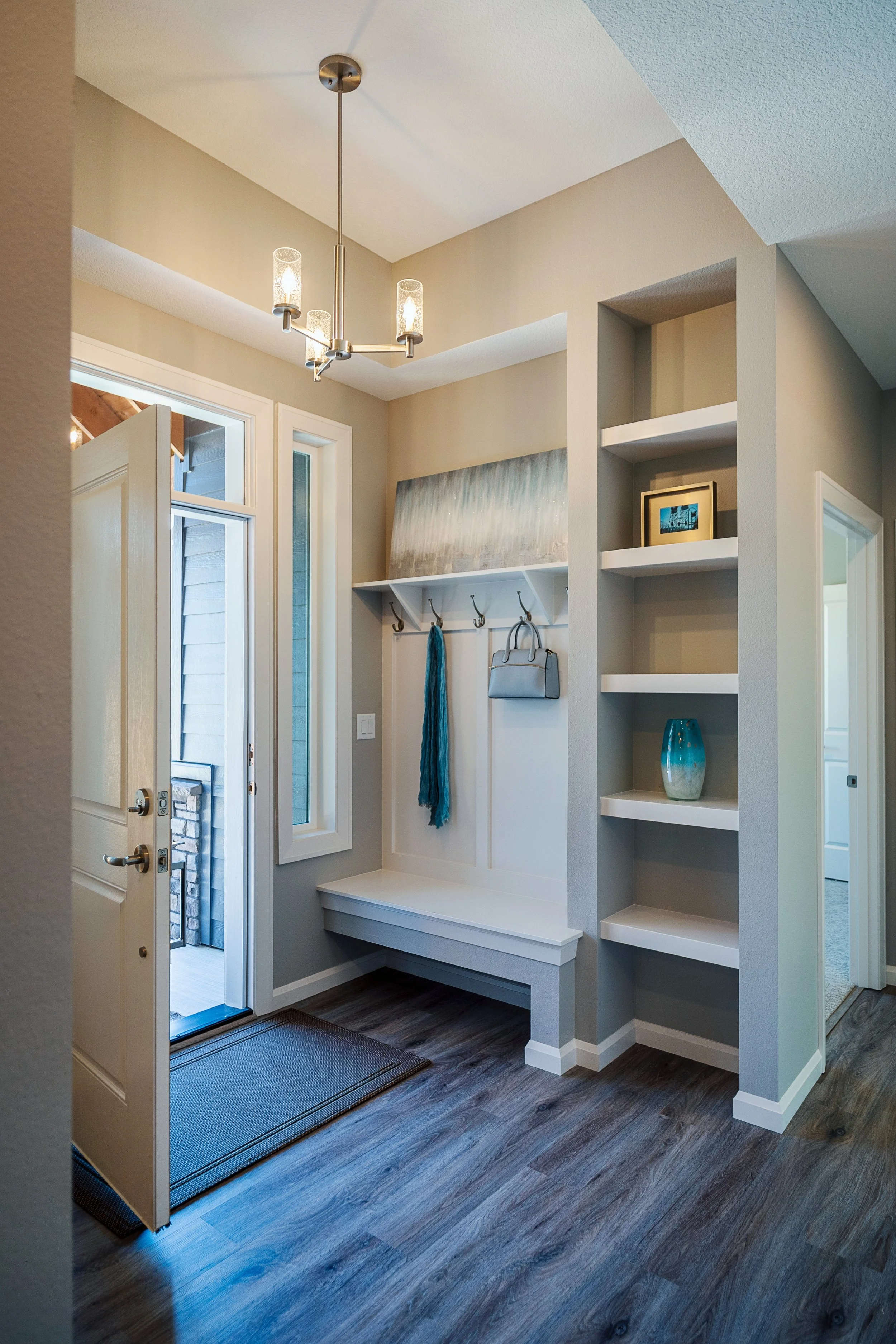 Entryway with a coat rack, shoes, a framed photo, decorative vase, and window near a front door.