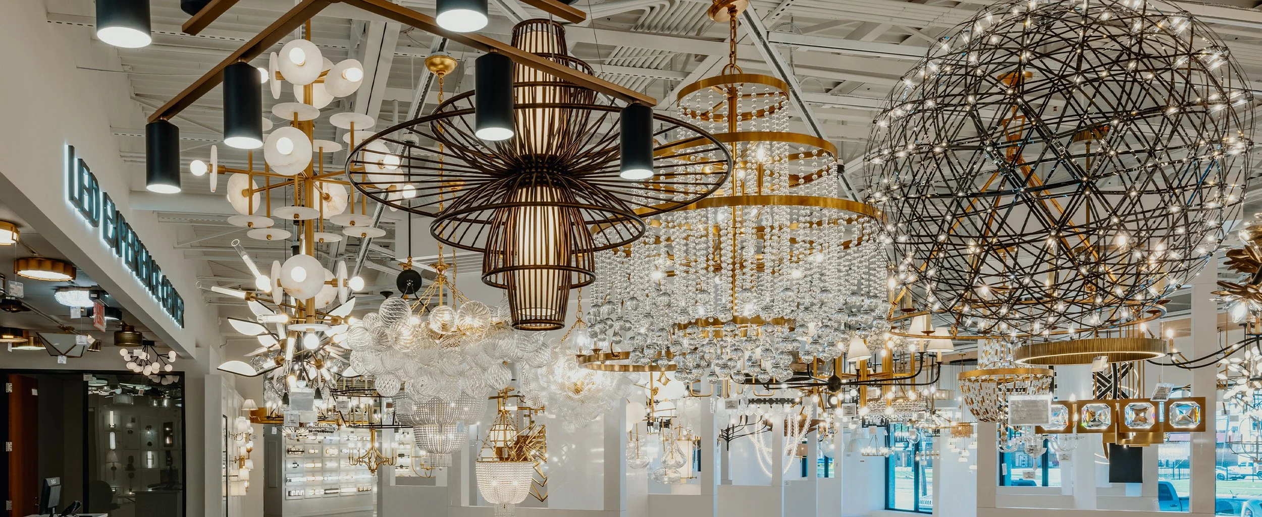 A lighting store interior with various modern chandeliers and pendant lights hanging from the ceiling.