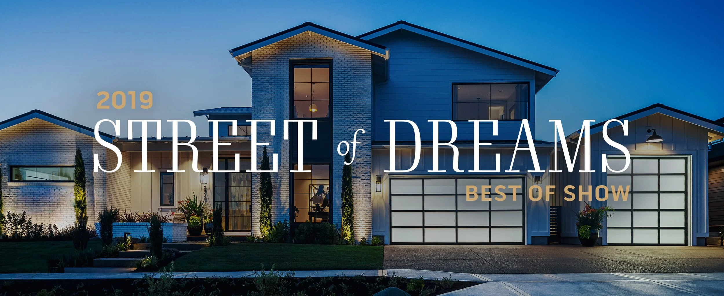 Modern house with a well-lit front yard during dusk, featuring a large garage with black-framed glass doors, various plants, and a clean driveway. Overlaid text reads '2019 Street of Dreams Best of Show'.