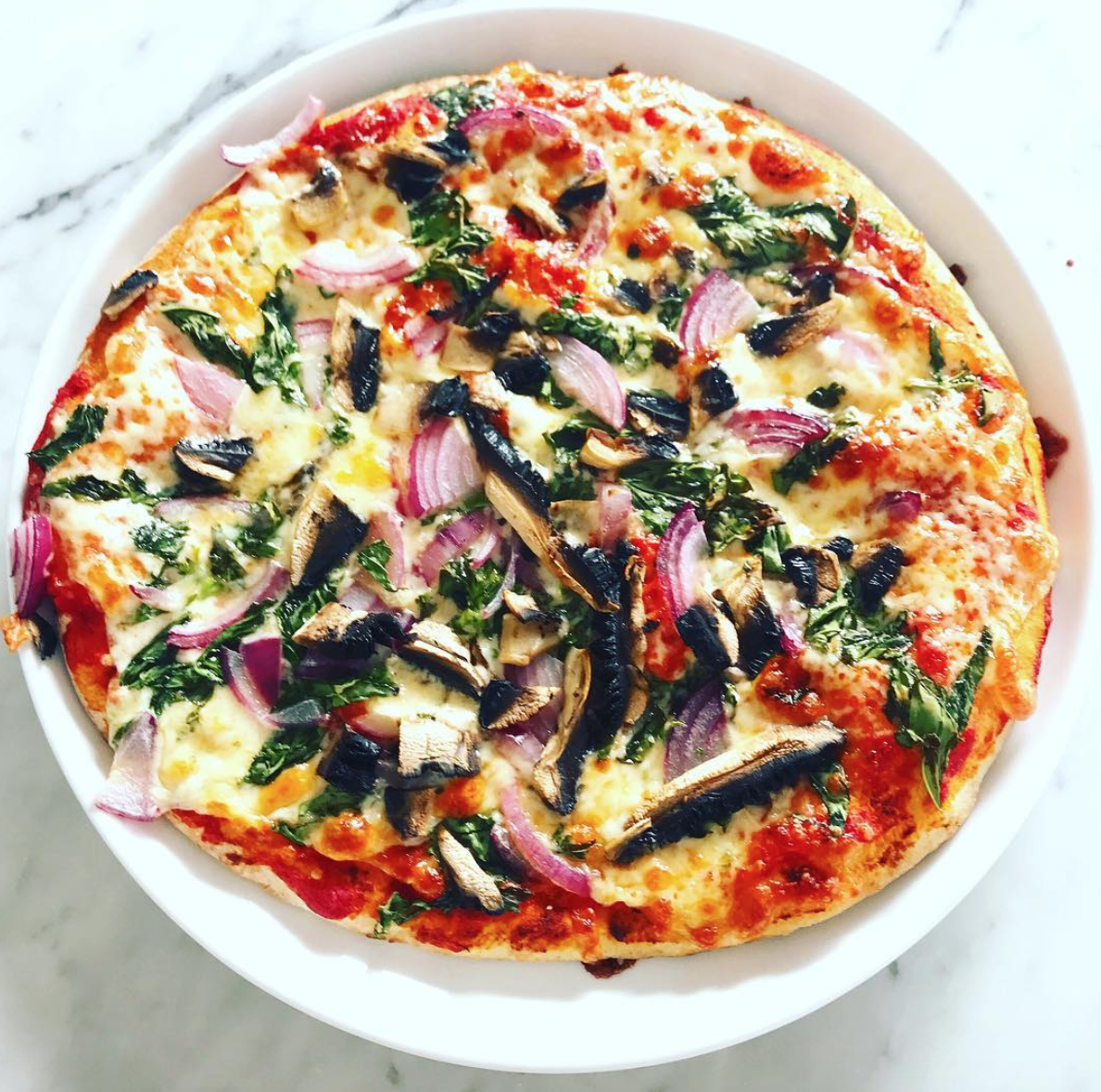 This pizza is topped with a tomato sauce, red onion, chilli flakes, basil, mushroom and mozzarella cheese.