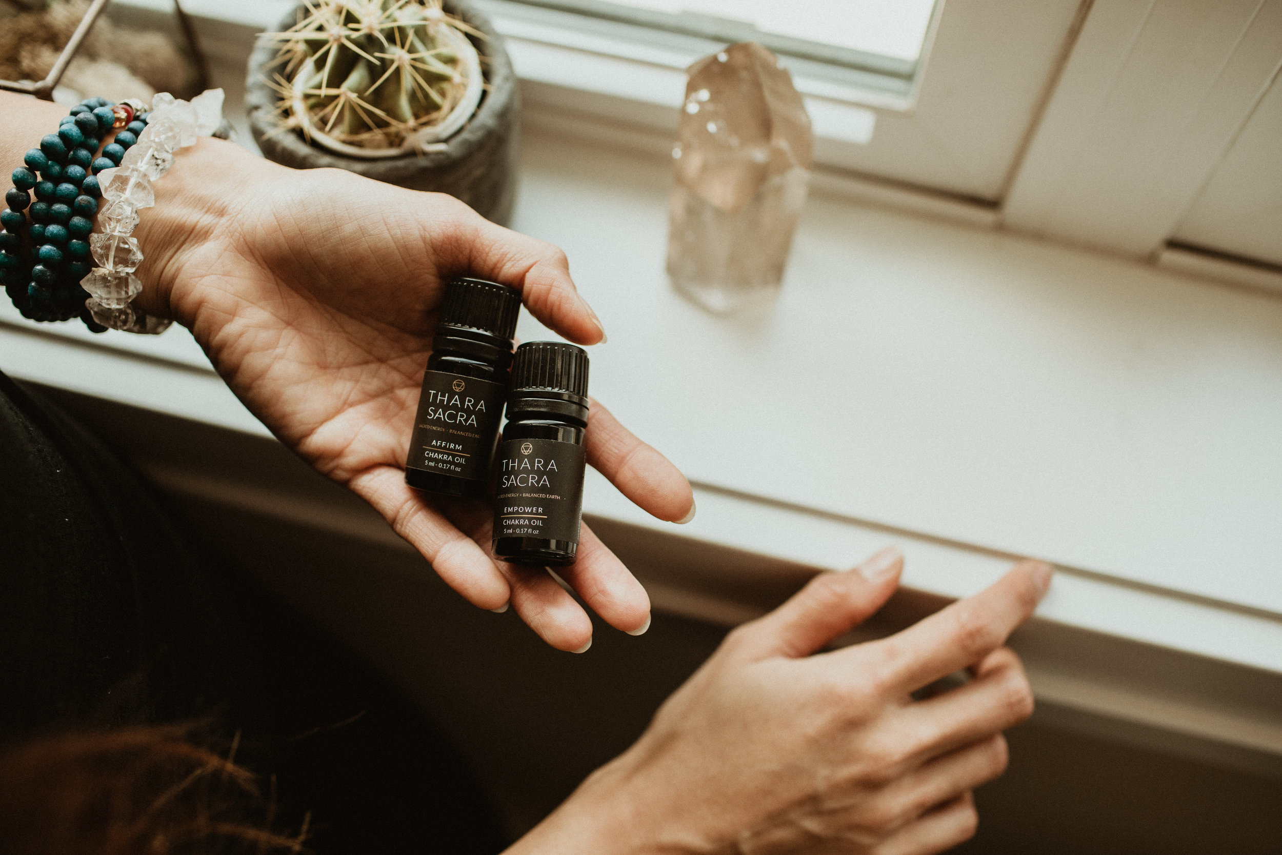 A woman holding Thara Sacra Empower and Affirm Chakra oils