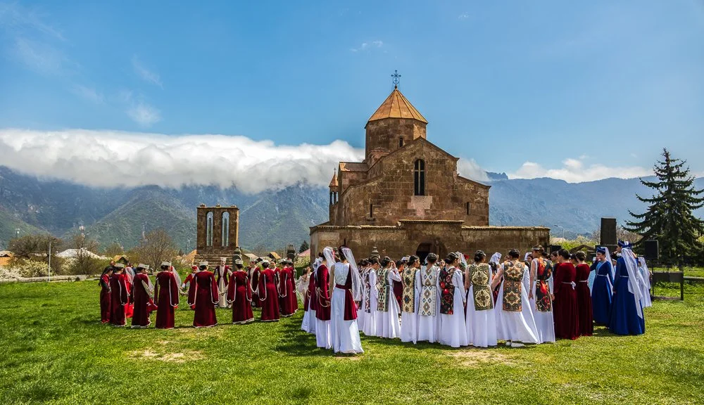  At  Odzun Monastery , a 6th-century domed basilica of pink stone sitting in the centre of the village, my timing was impeccable. A folk dance festival was underway outside the church, women and girls in traditional dress performing on the grass.  