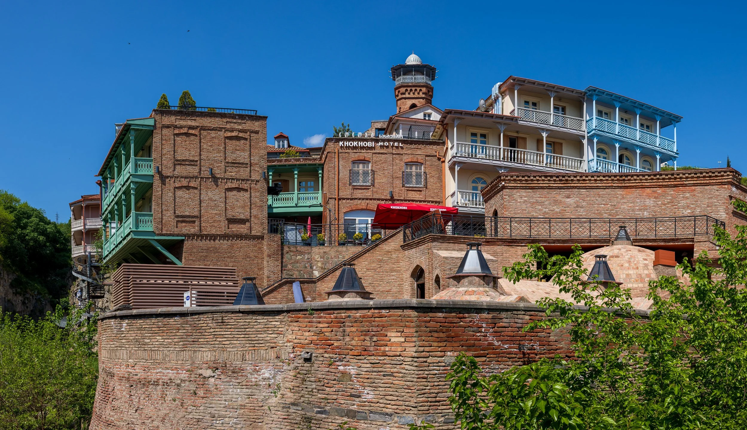  Old Town balconies - Carved wooden balconies cling to the cliffside in Tbilisi's Old Town, layered brick and timber stacked above the rock. 