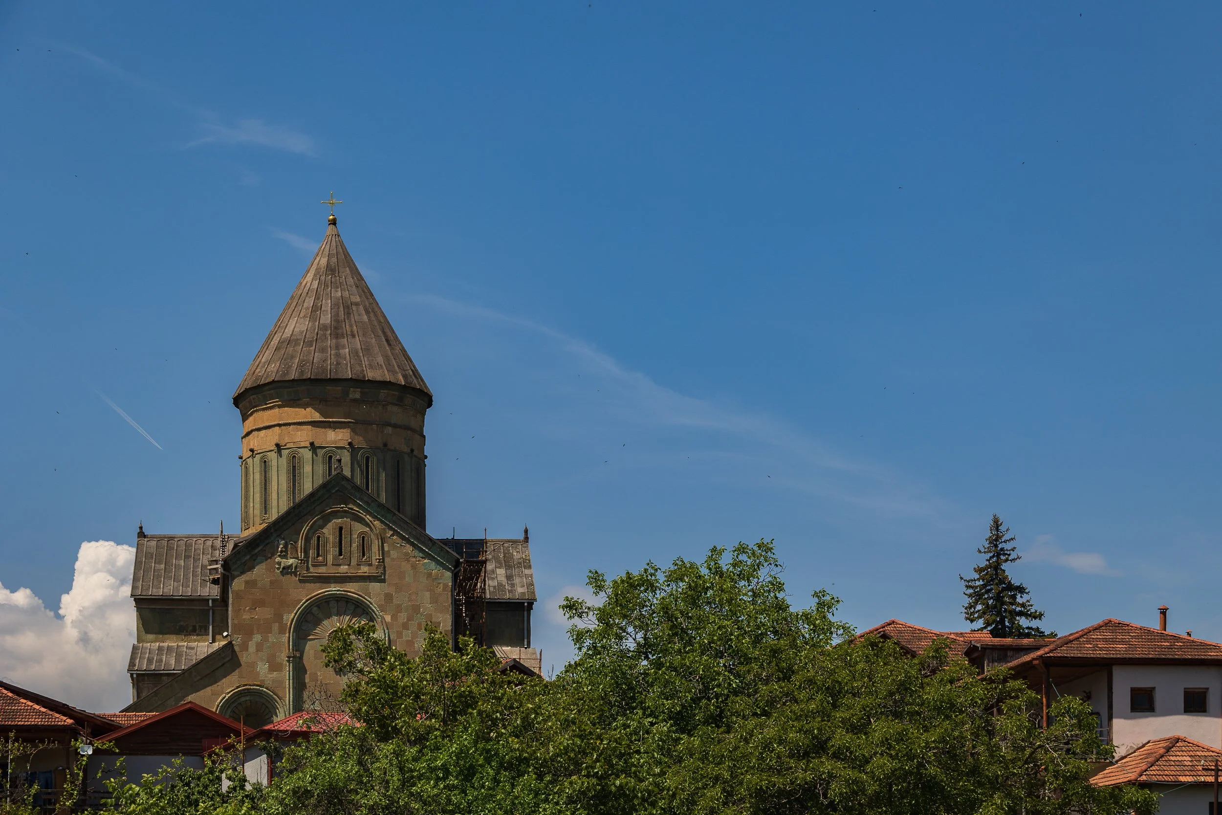  Mtskheta (cathedral/vendors) - Svetitskhoveli Cathedral rises above the old fortified walls, vendors hanging carpets, bags, and souvenirs along the fence below. 
