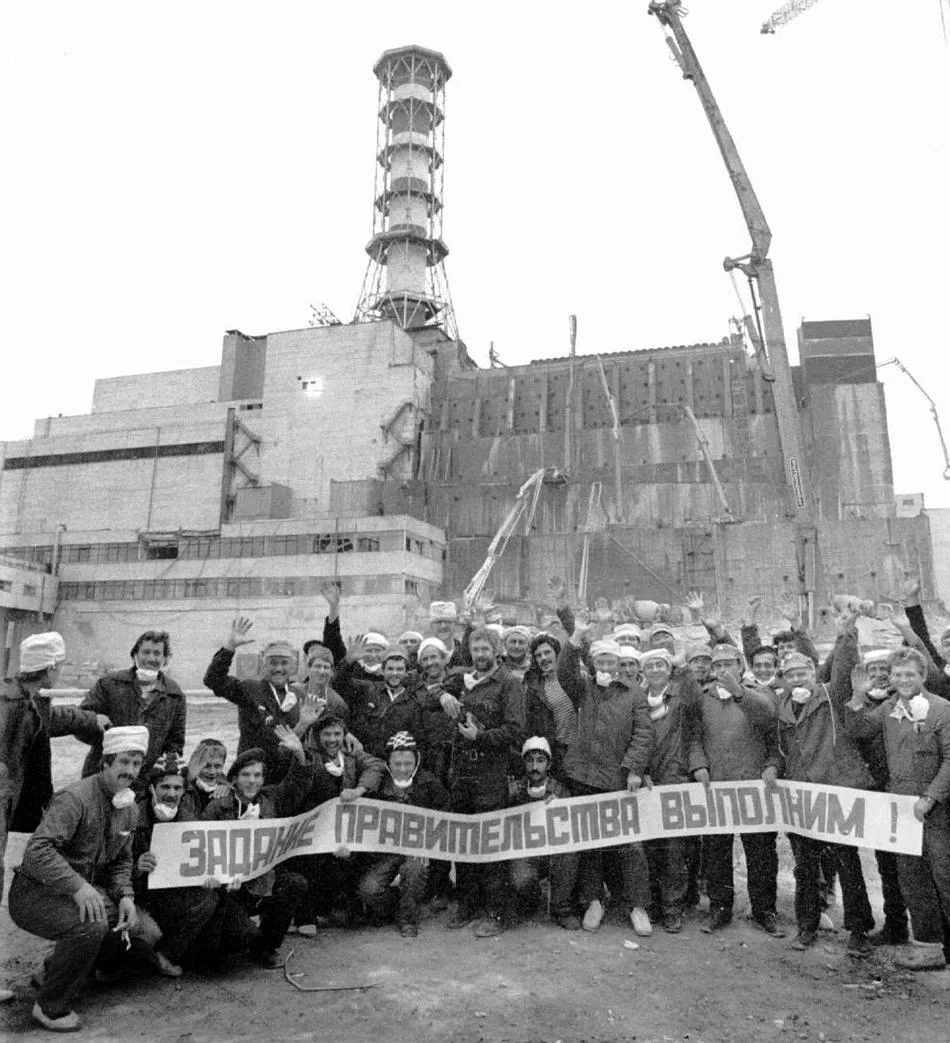 liquidators in front of the concrete sarcophagus they created; their banner reads “We will fulfill the government’s order!” (source: annemalu.wordpress.com )