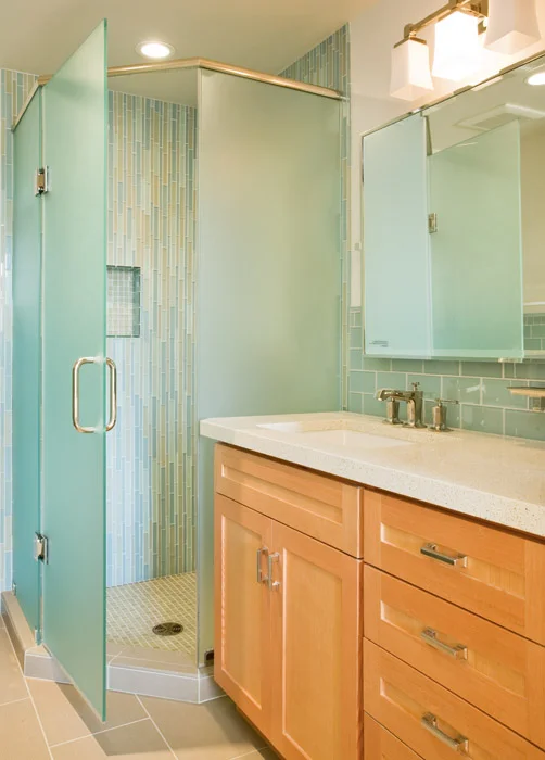 Glass tile with Douglas Fir cabinets complementthe light airy feel of the second bath. Heavy glass doors complete the angled shower with vertical tile installation for a reed like feel.