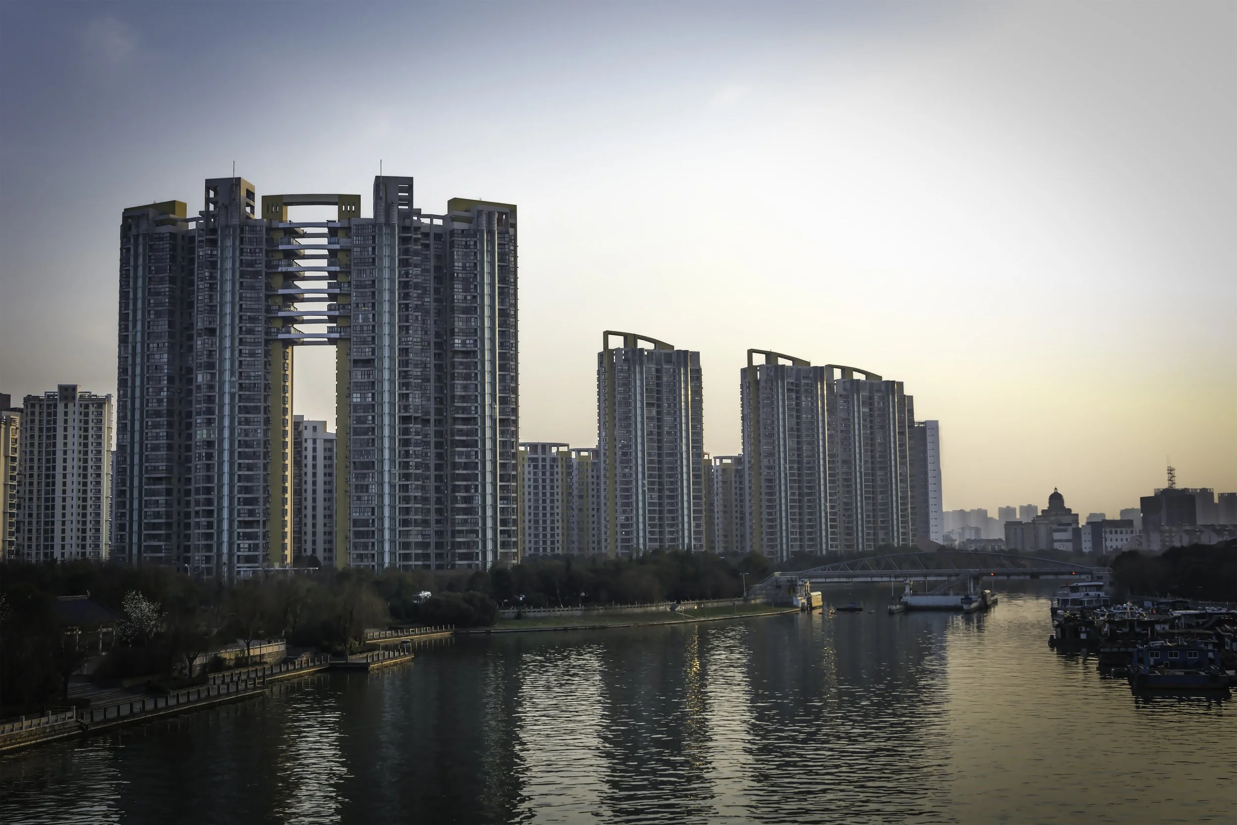Cityscape with tall modern high-rise buildings along a river at sunset