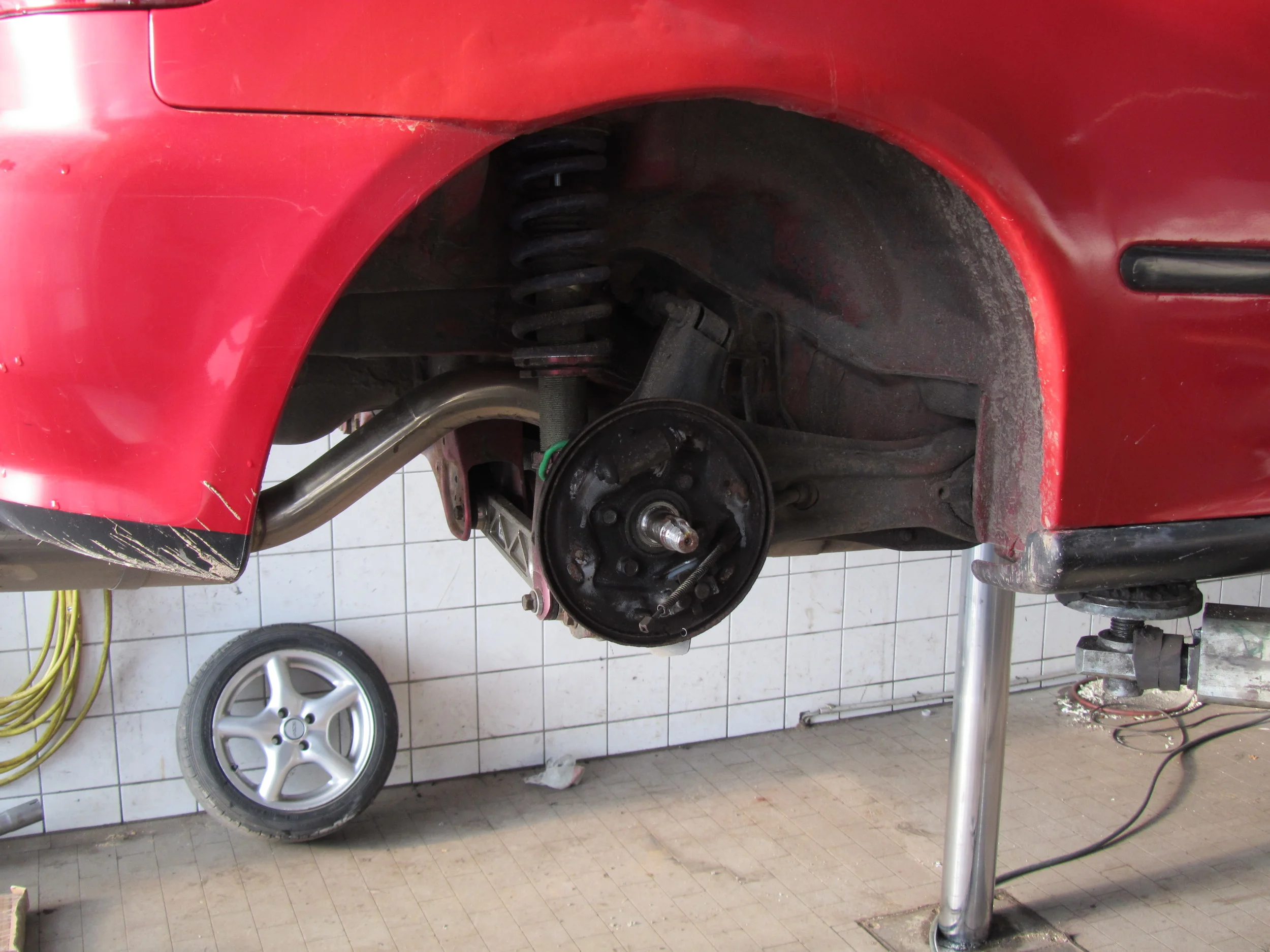 1. Arriving at the garage shortly after 8 am, I put the car up in the air and together with one of the mechanics, we set out to “crack” the drum brakes open to remove them and disconnect the handbrake cable.