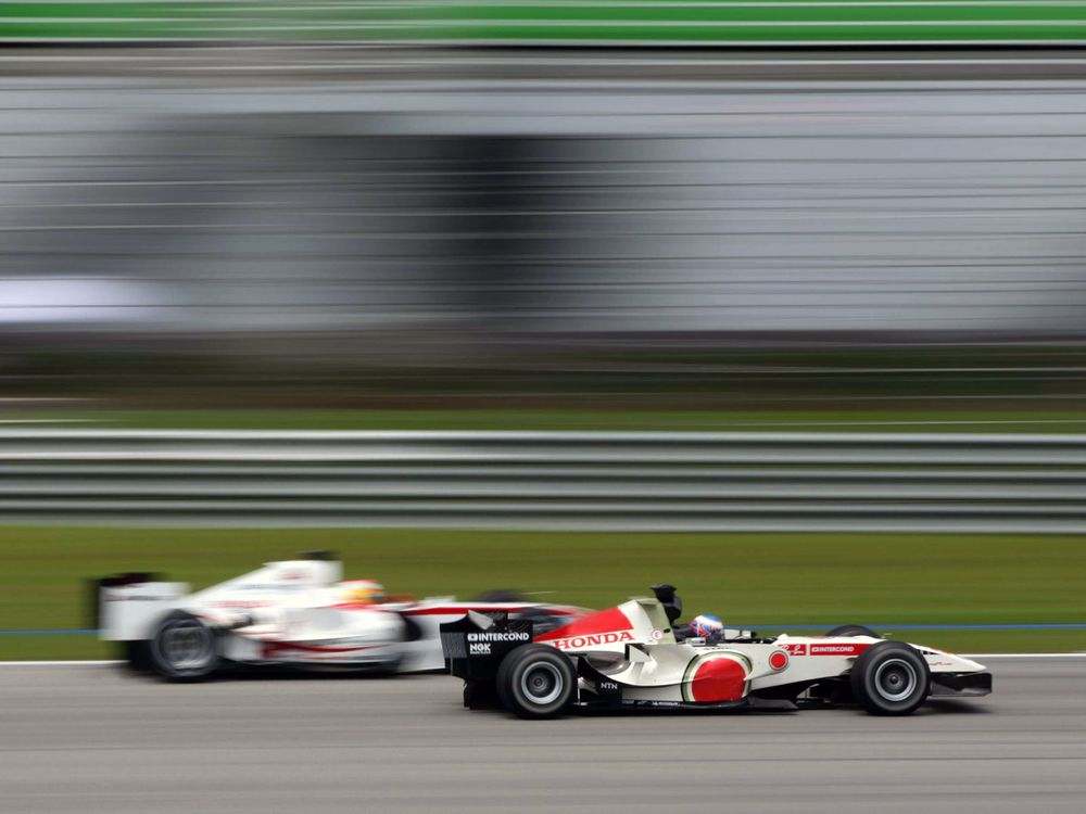 The Honda of Jenson Button blasting pass the Super Aguri of Yuji Ide at Sepang.