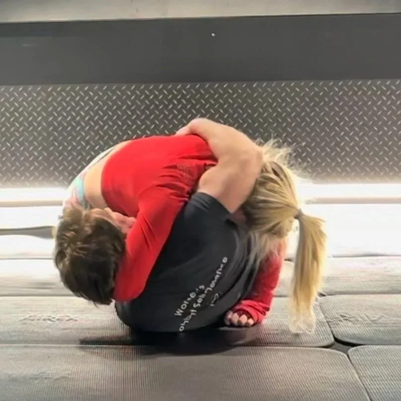 Instructor-led grappling drill on padded mats during a grappling training session.