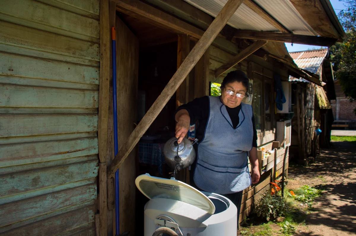The machine does not function well so she uses her hands to clean the clothing. Hot water makes it feel better on her skin.