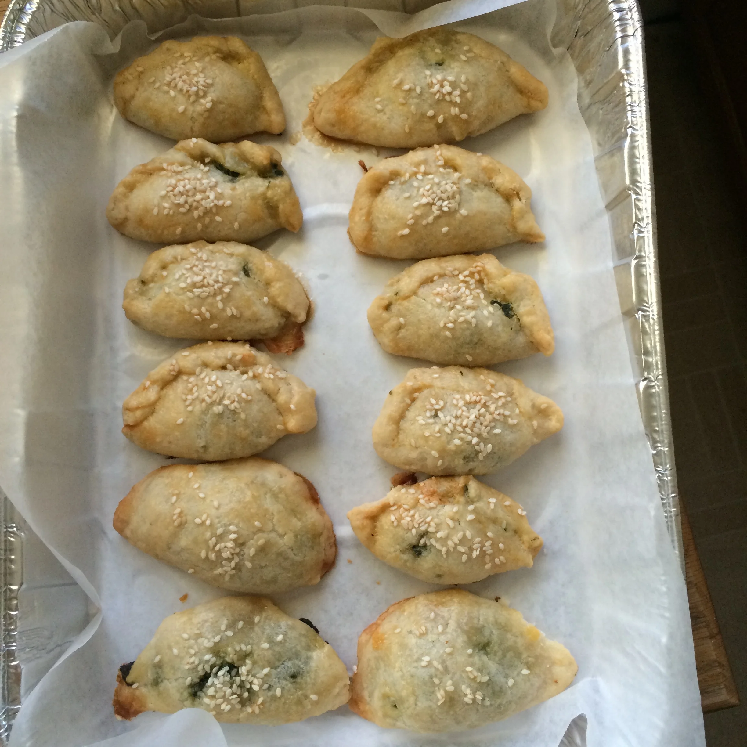 Borekas , stuffed pastry turnovers, finished with sesame seeds and packed to go.
