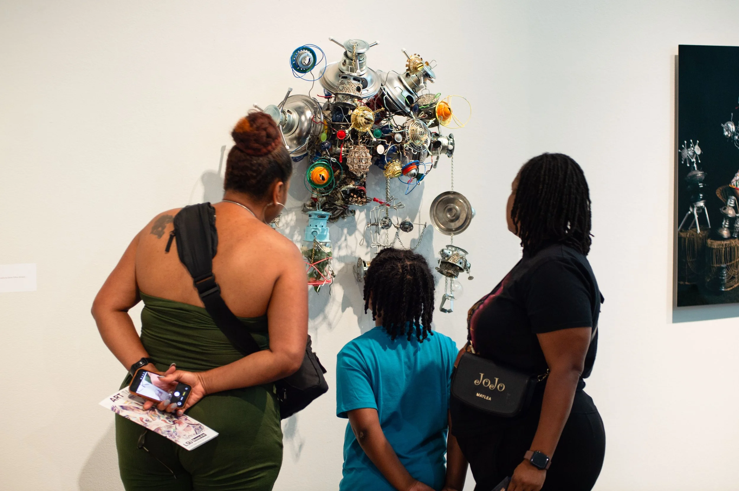 Three people looking at an artwork in the gallery.