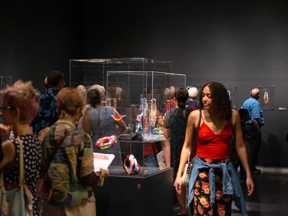 Group of visitors gathered around a glass display case in an exhibition space.