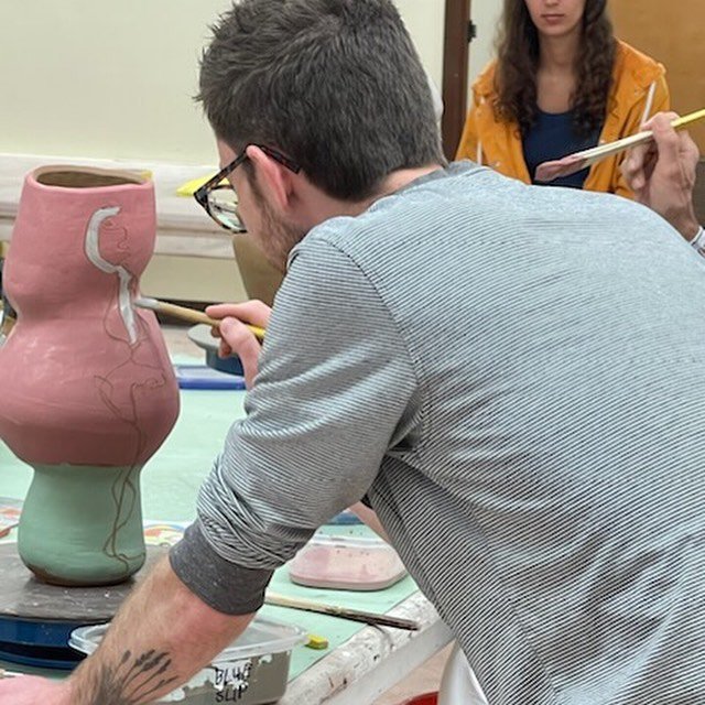  Matt Jones (LSU MFA Ceramics) applying slip to Darré’s ceramic works.  