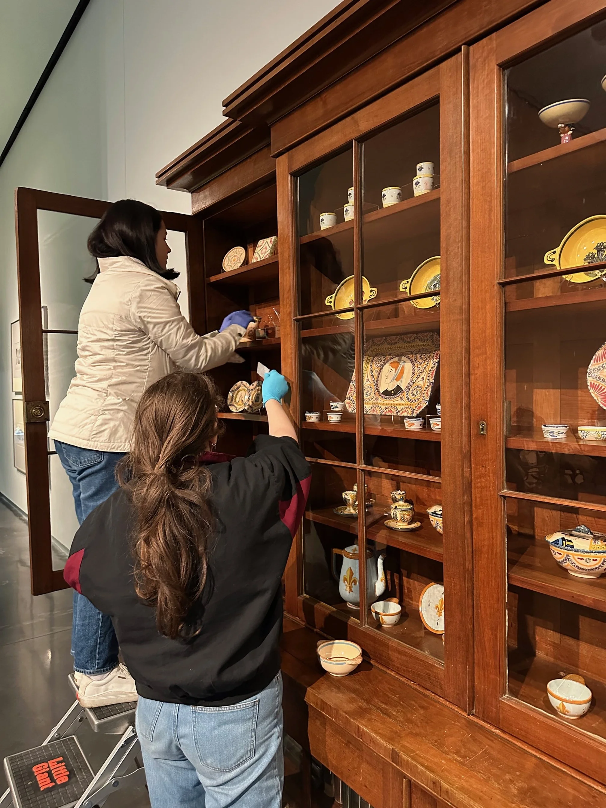  Sarah Ducote, Curatorial Graduate Assistant, and Melissa George, Collections Graduate Assistant, installing Quimper Pottery at the LSU Museum of Art. 