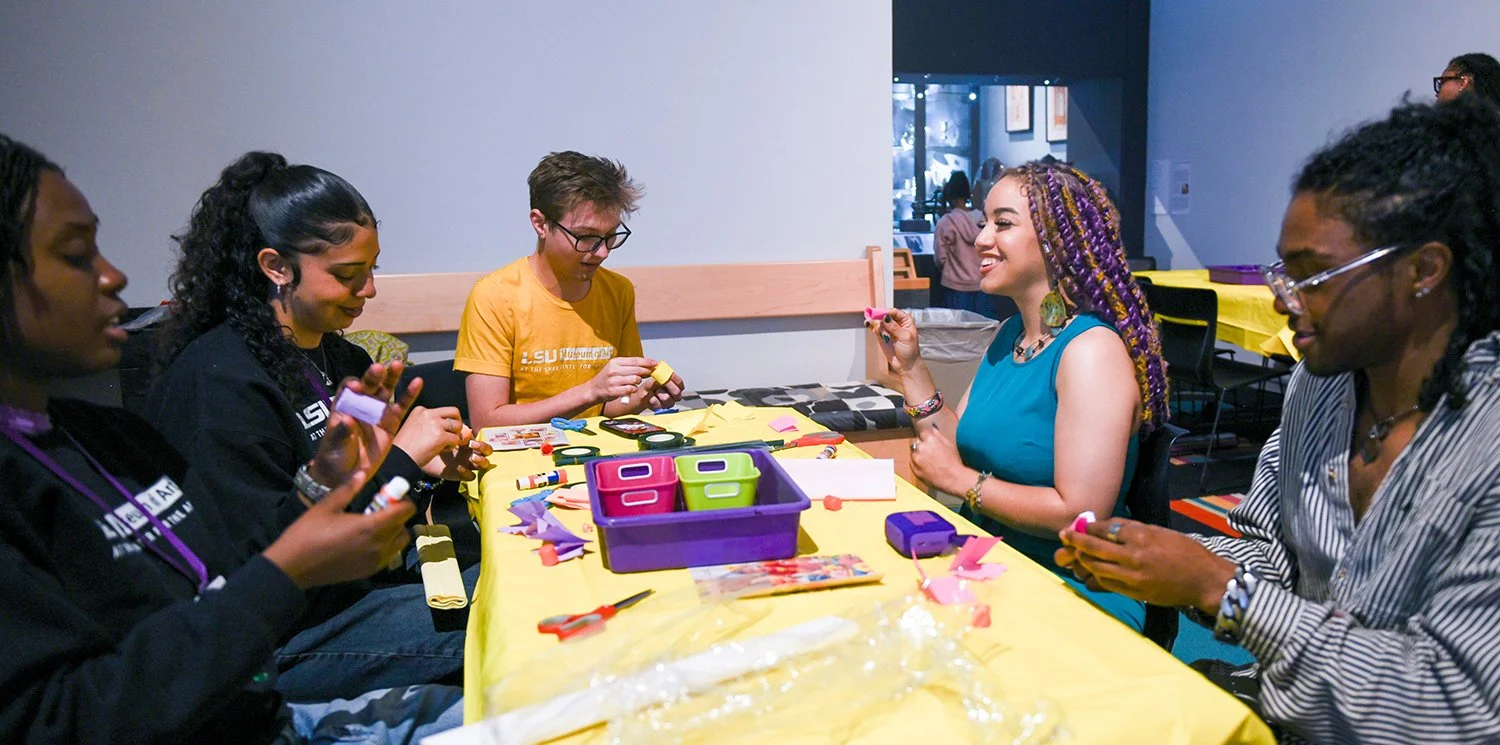 Five people sitting at a table doing an art project.
